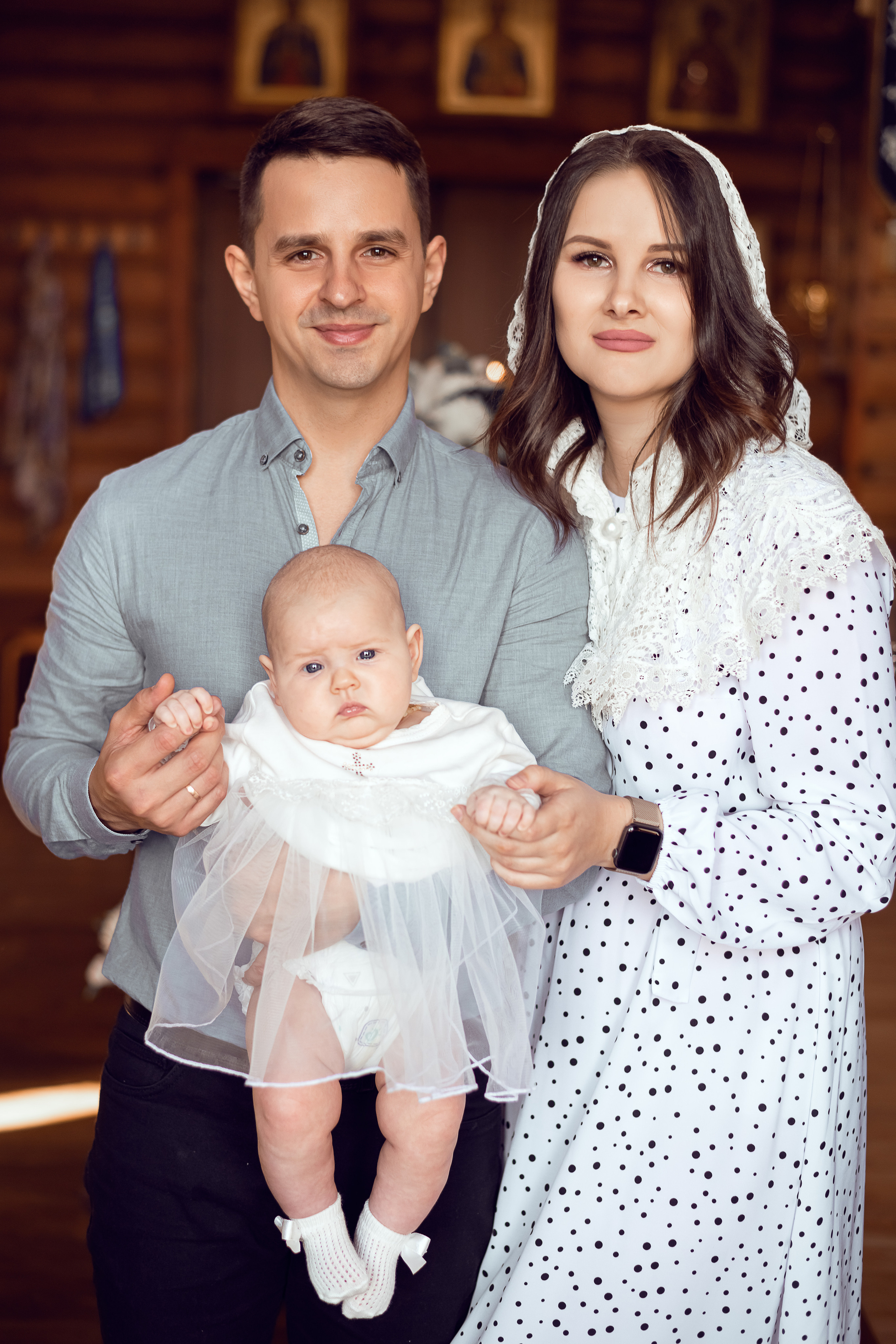 Родители стоят в храме со своей малышкой