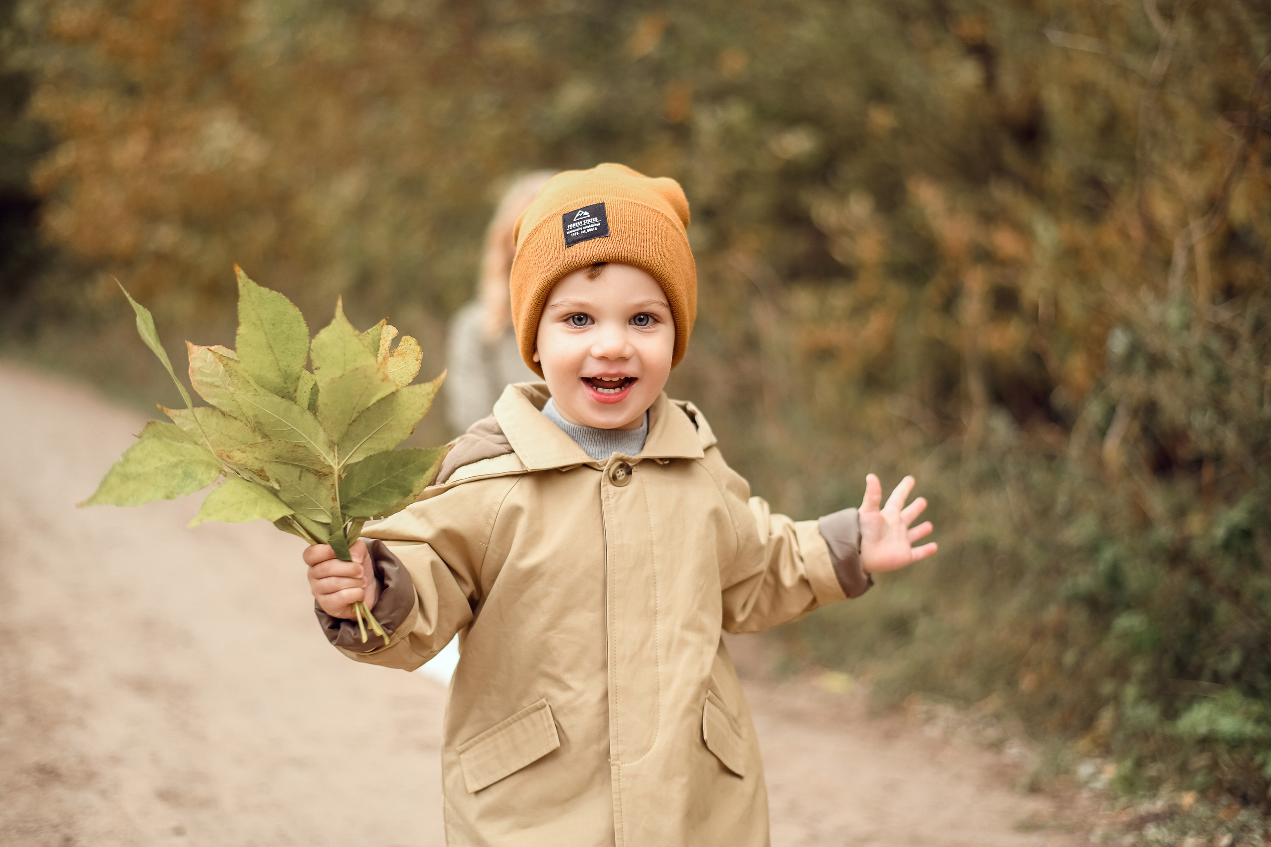 Маленьким мальчик бежит с осенним букетом в лесу