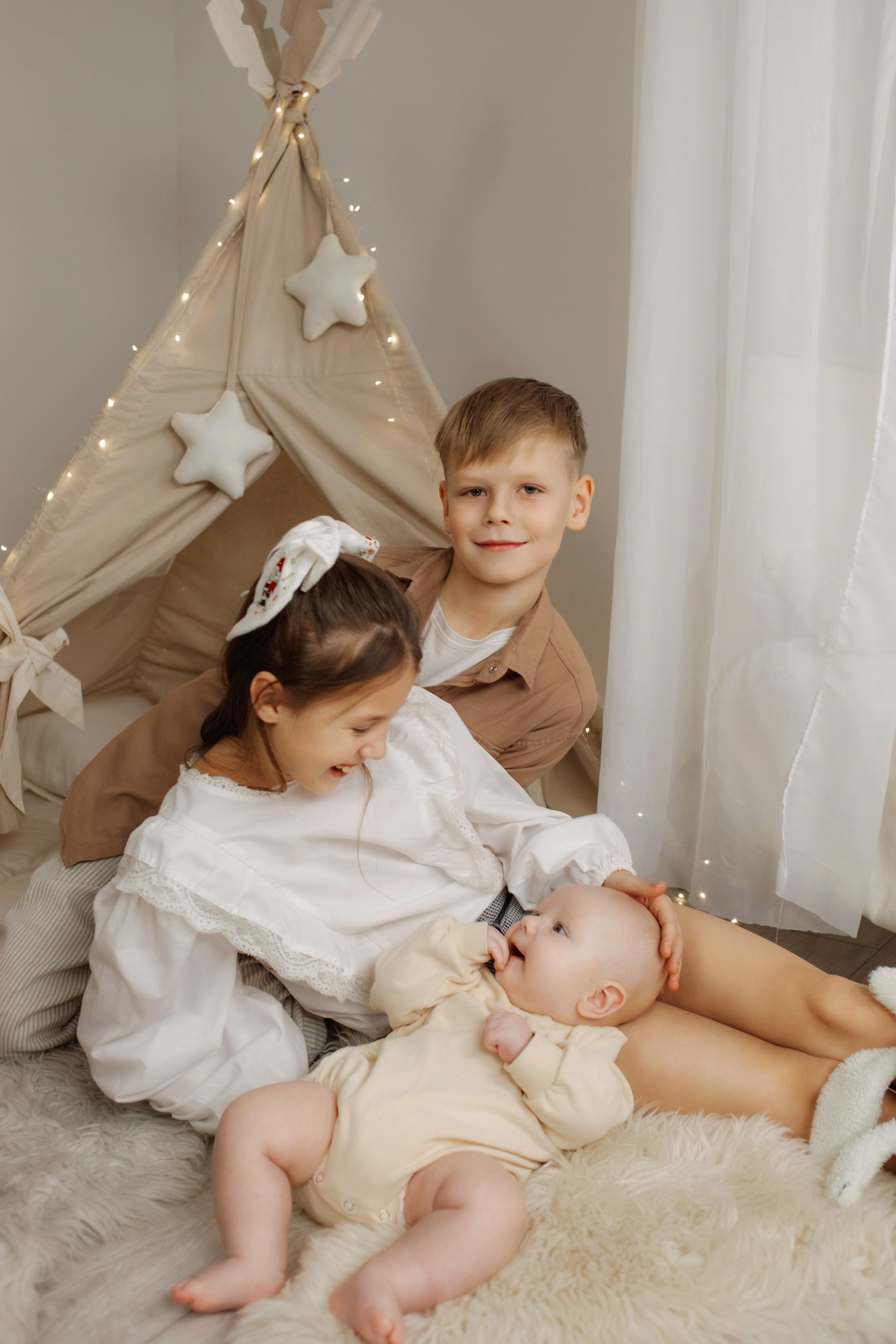 Классическая новогодняя фотосессия в светлой студии у елки, дети играют друг с другом