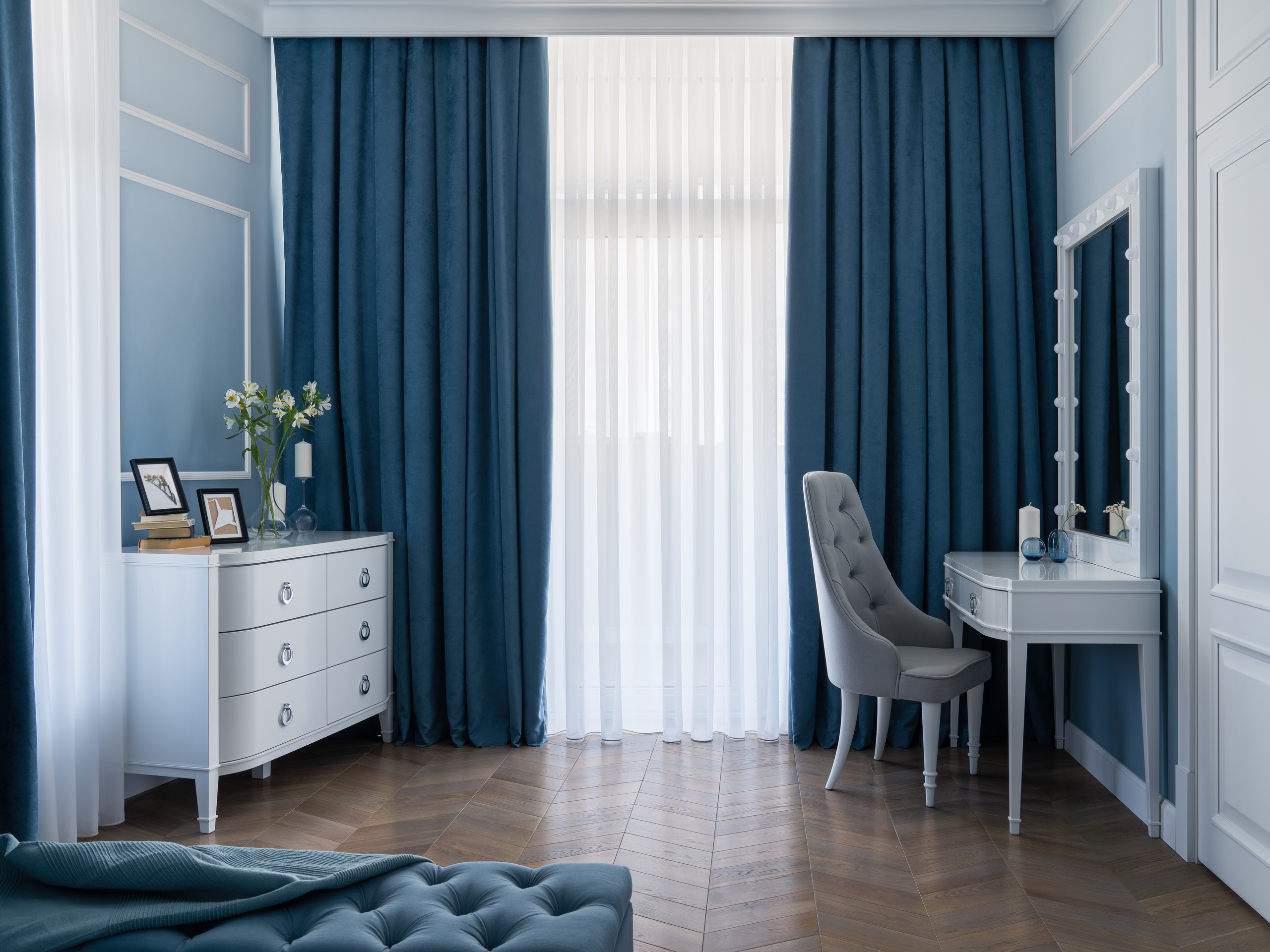 Интерьер спальни в голубых и синих тонах с элегантным туалетным столиком, серым креслом и гардинами, создающими уютную атмосферу. Дизайнер Евгения Княжева, интерьерный фотограф Сергей Денисенко.