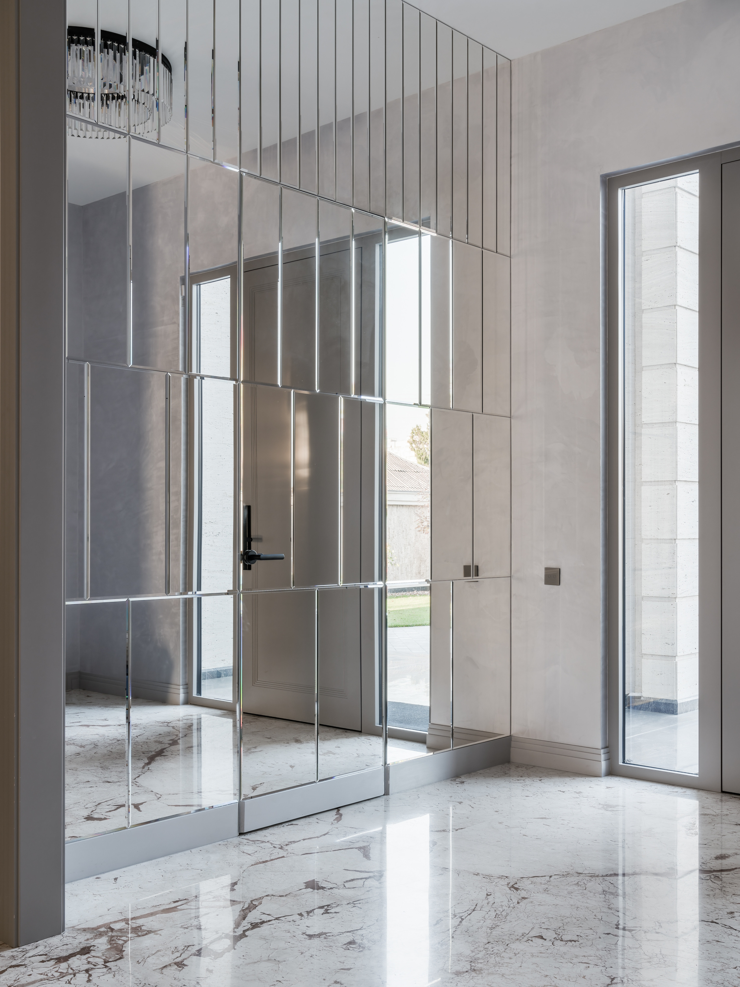 Современная прихожая с зеркальной стеной, мраморным полом и панорамным остеклением, наполненная светом. Интерьерное решение от дизайнера Анастасии Ковалевской, автор фото — Сергей Денисенко.