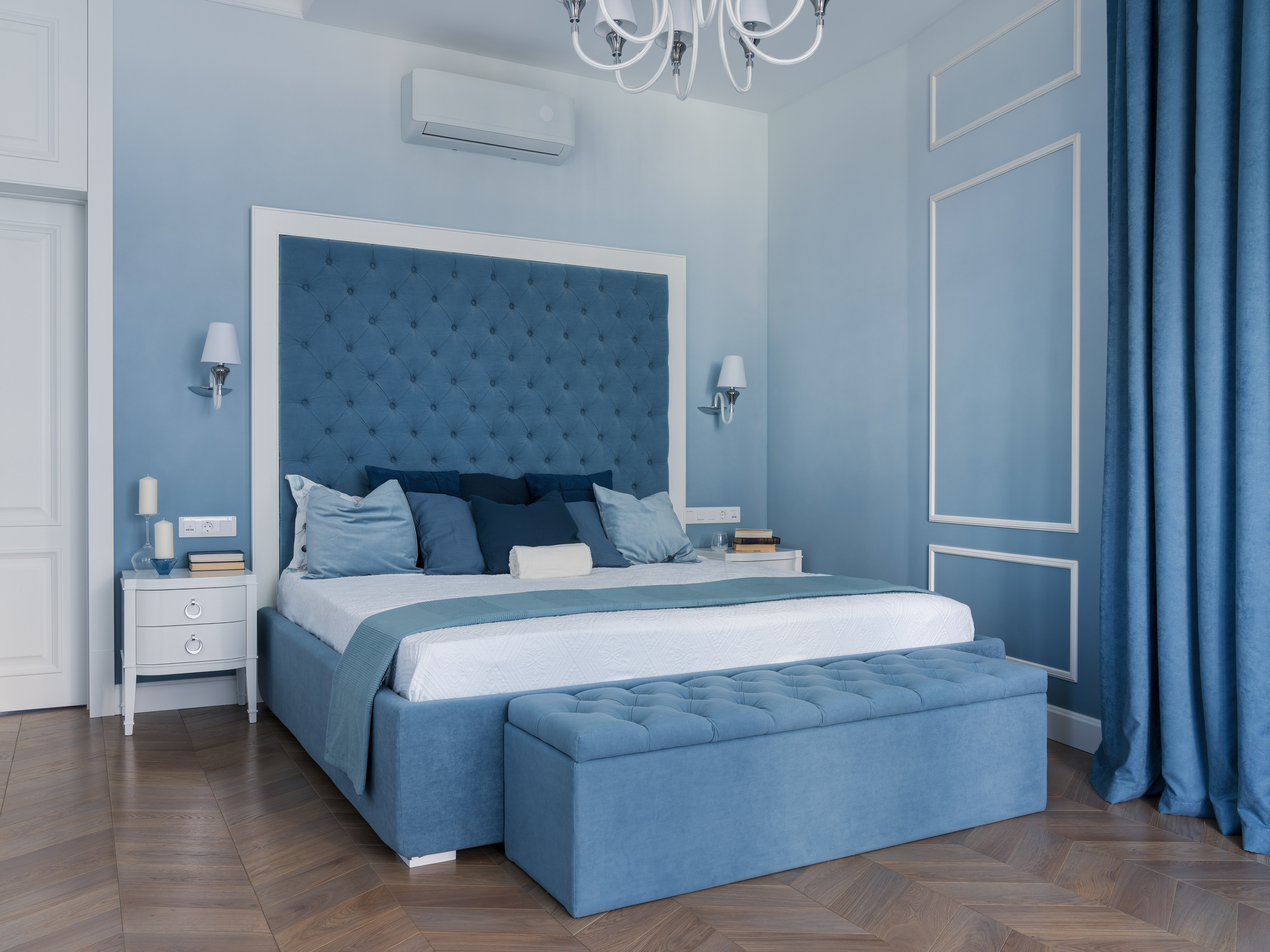 Стильная спальня в синих оттенках с кроватью, мягкой скамьей у изножья, настенными бра и белой люстрой. Дизайн Евгении Княжевой, интерьерная фотосессия Сергея Денисенко.