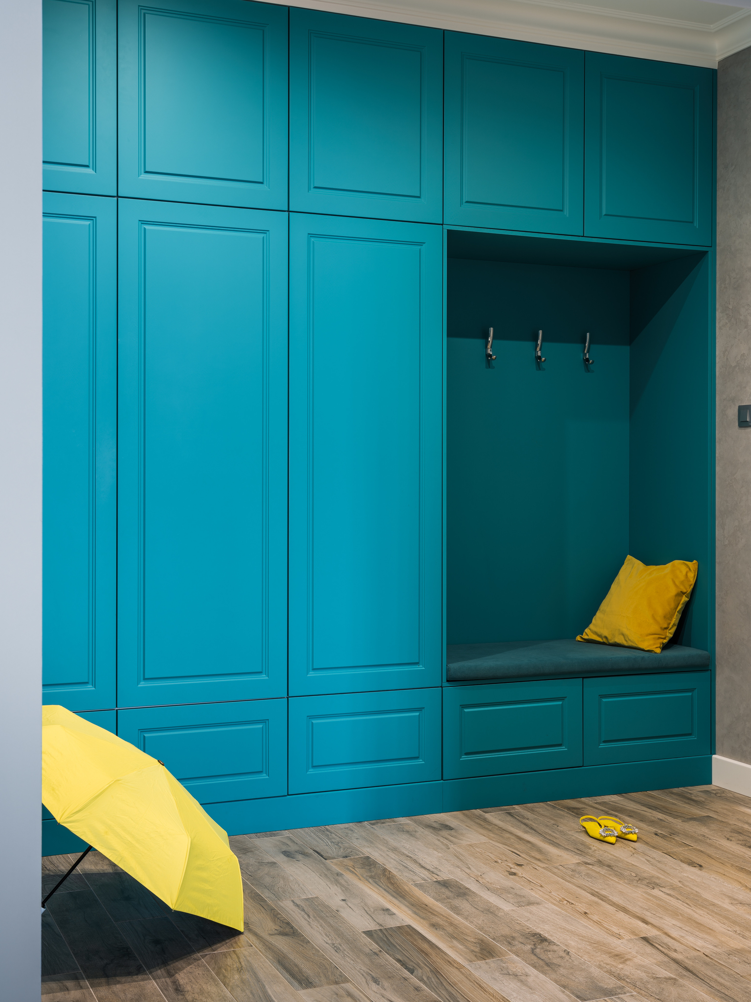 Интерьер прихожей с большим встроенным шкафом в бирюзовом цвете, мягкой скамьей и акцентами в жёлтом. Проект дизайнера Евгении Княжевой, фотосъёмка Сергея Денисенко.