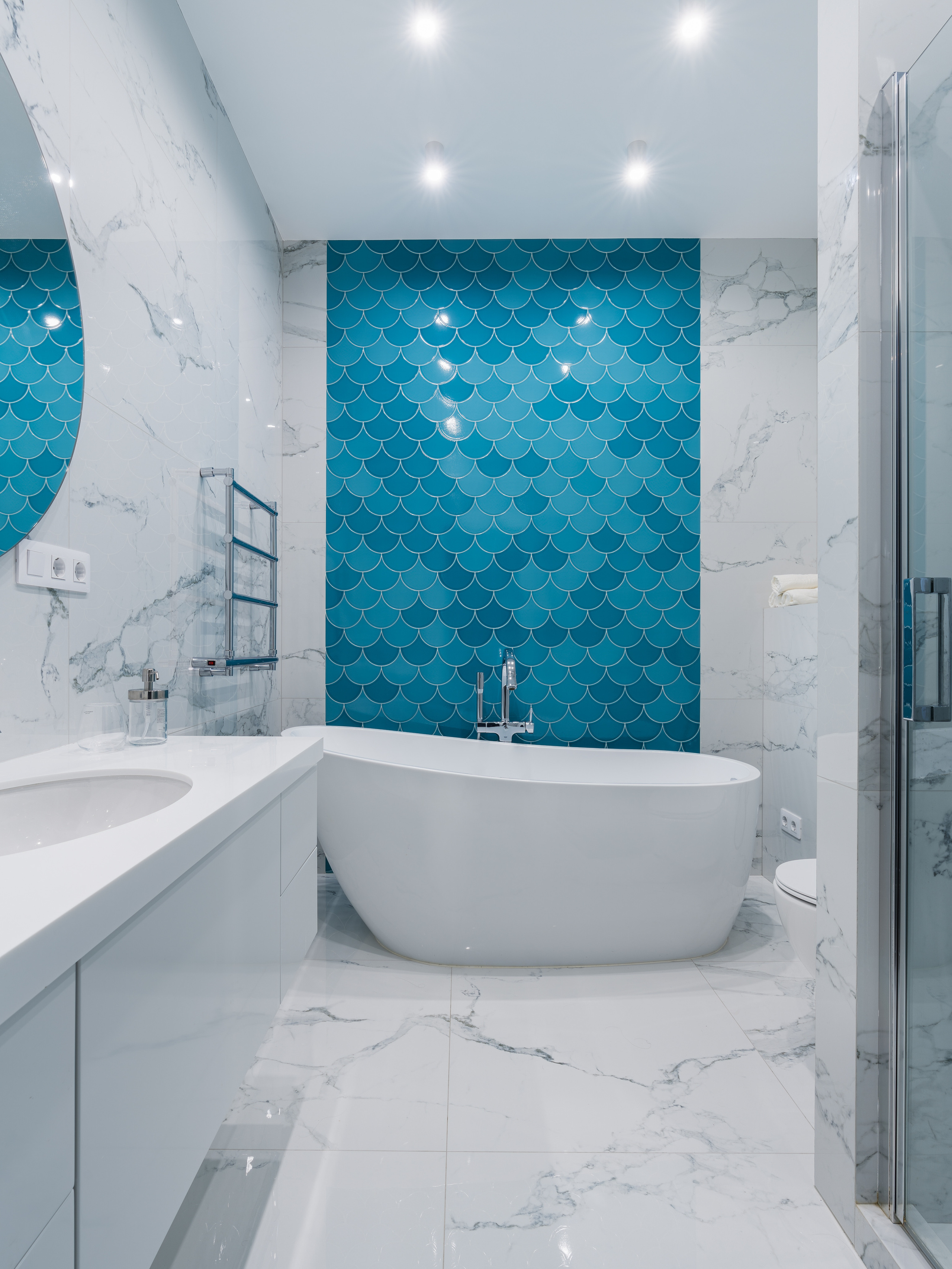 Роскошная ванная комната с отдельностоящей белой ванной, мраморной плиткой и акцентной стеной из керамики в форме чешуи насыщенного синего цвета; уникальный проект Евгении Княжевой, фотосъёмка интерьера Сергей Денисенко.