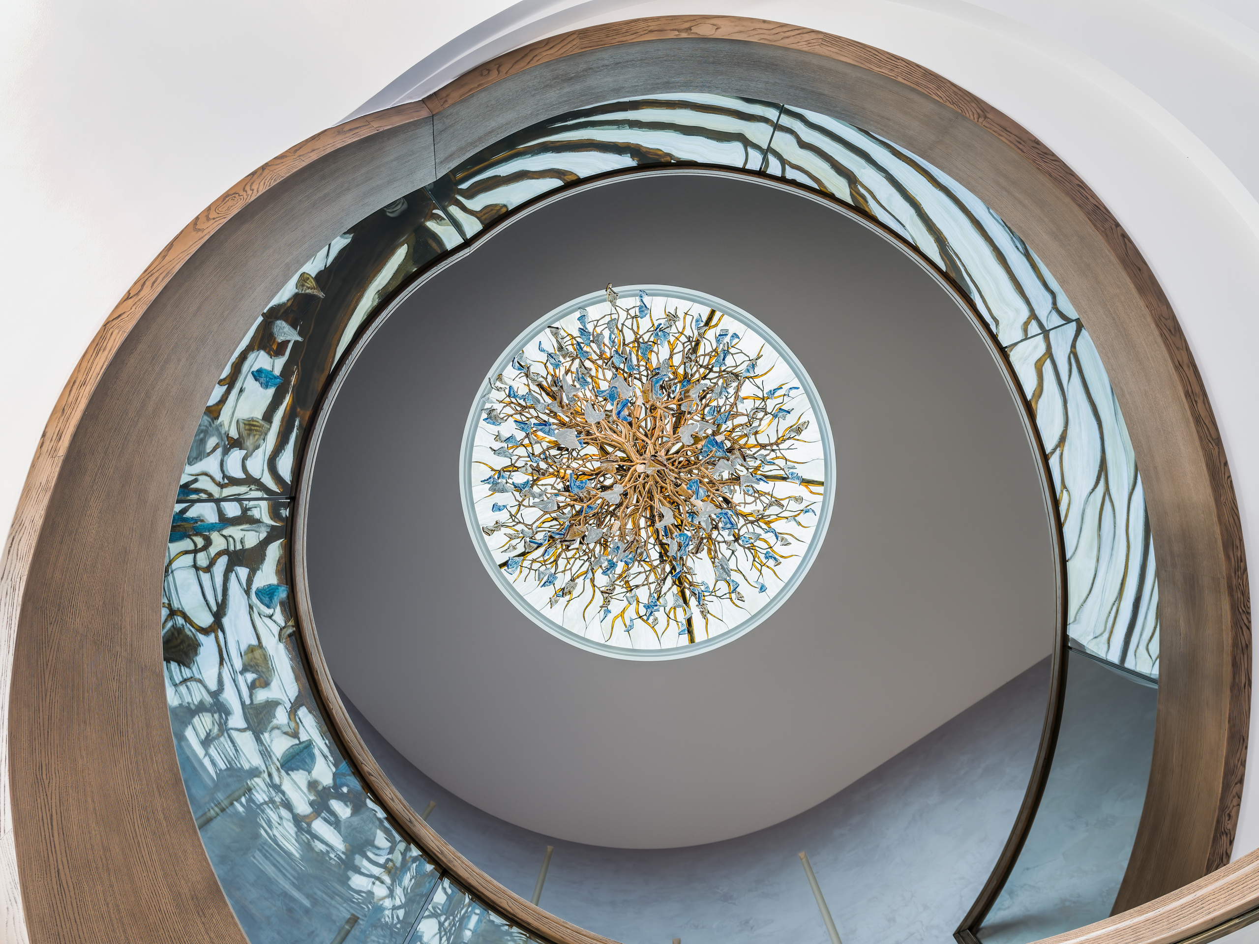 Декоративная люстра в форме ветвей с голубыми и золотыми подвесами, размещённая под круглым потолочным окном, подчеркивает художественный стиль, интерьерный проект Анастасии Ковалевской, фотограф Сергей Денисенко.