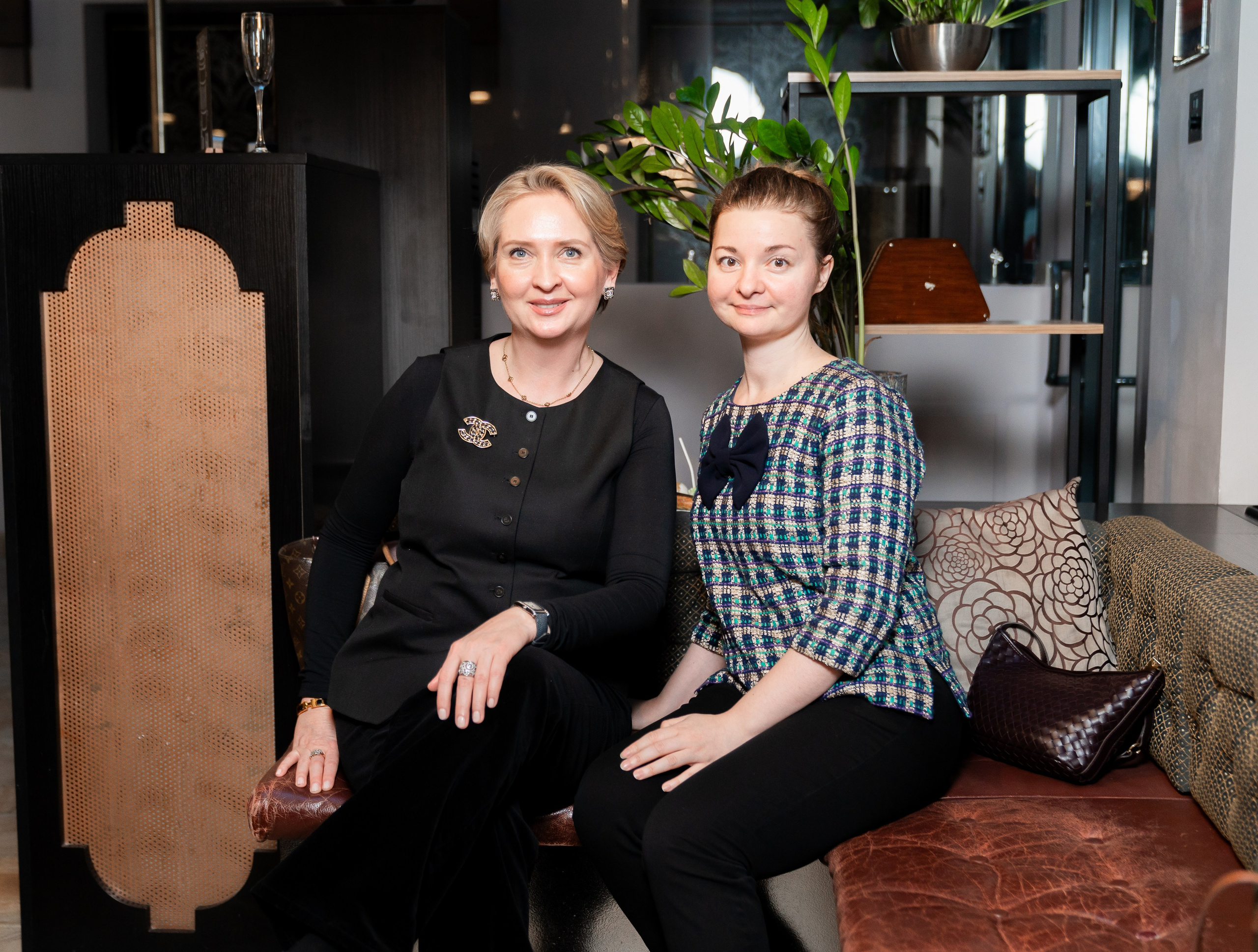 Две элегантные женщины позируют на кожаном диване в интерьере Radisson Sonya Hotel. Фото Евгения Мальцева.