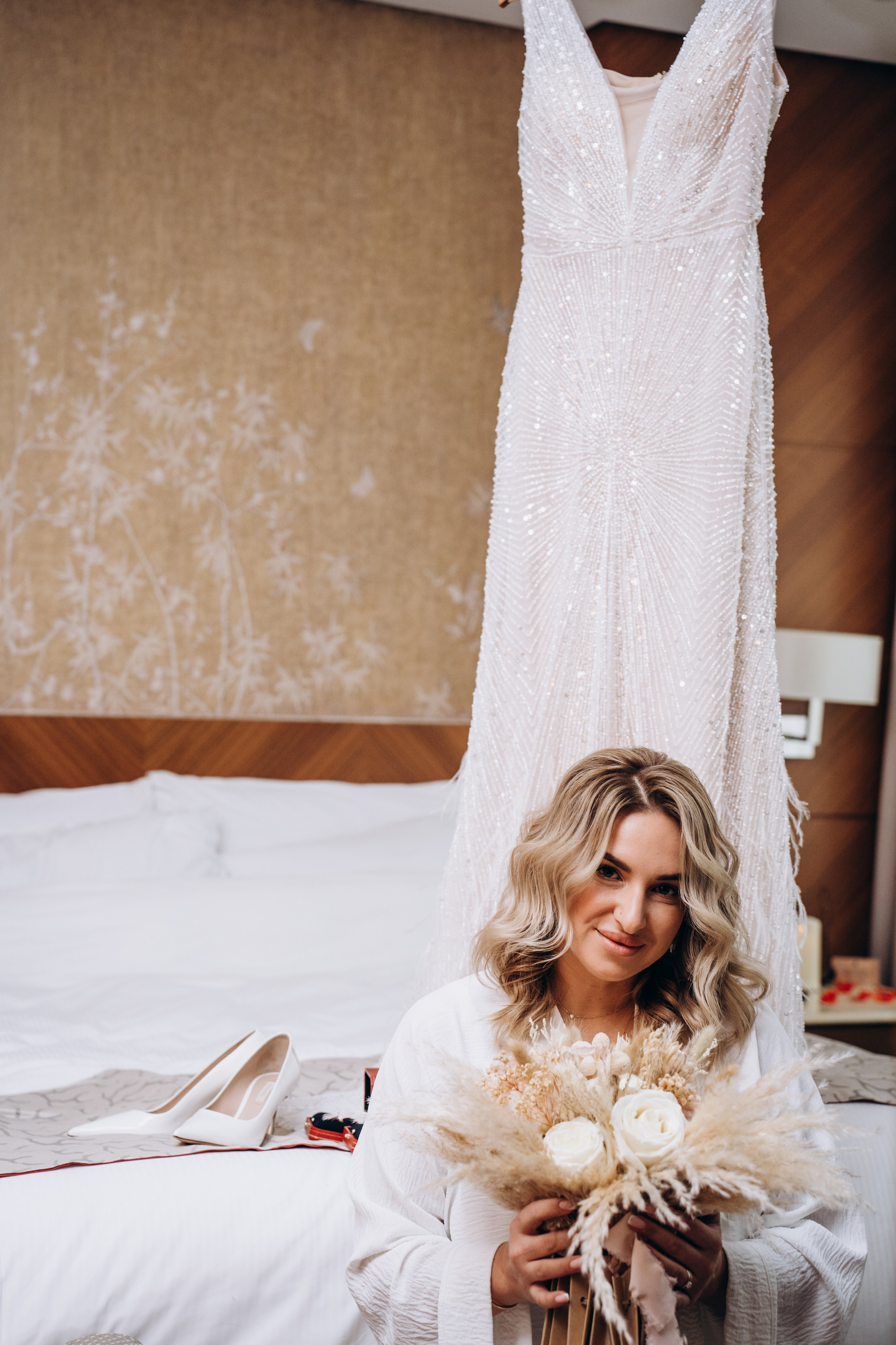 Невеста улыбается, держась за букет — эмоциональные моменты сборов, наполненные ожиданием и радостью.