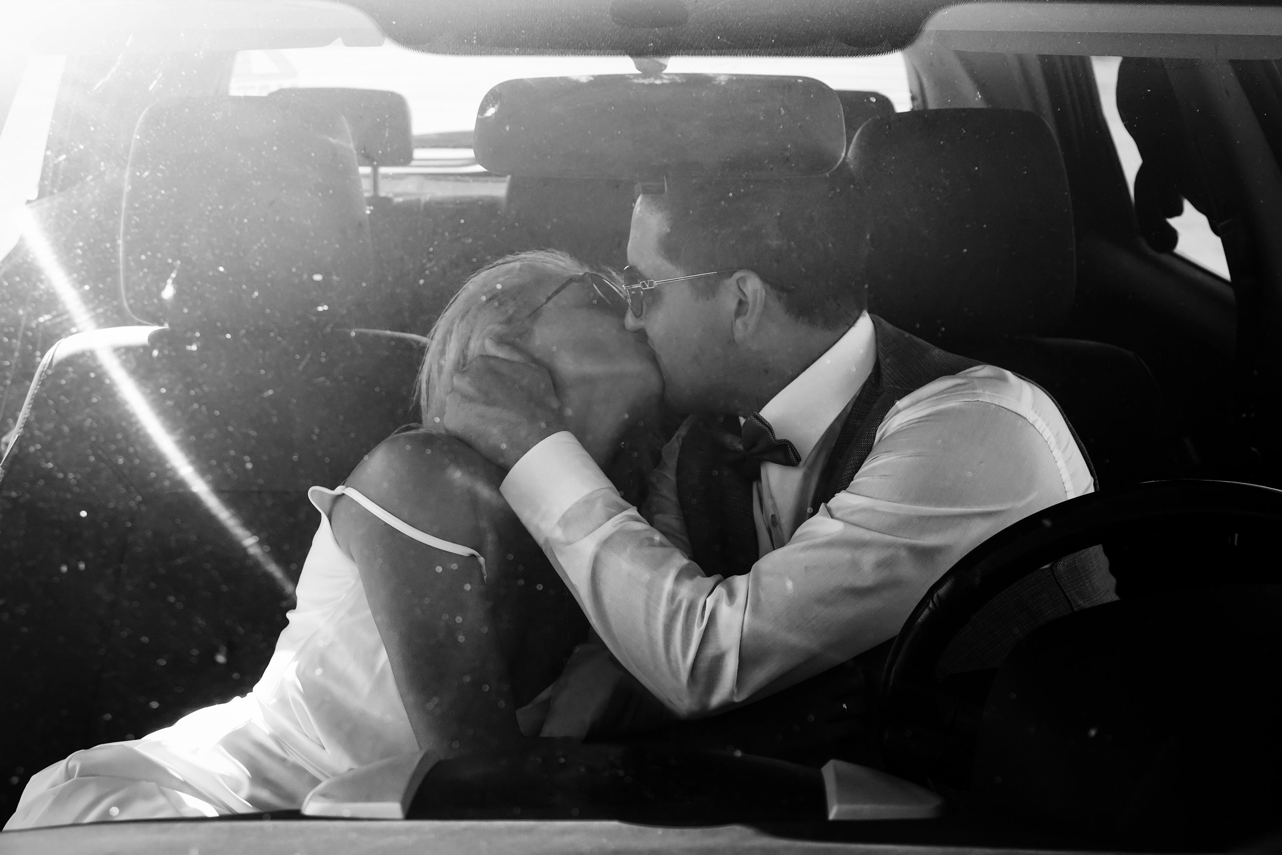 Жених и невеста целуются в машине, съёмка через лобовое стекло