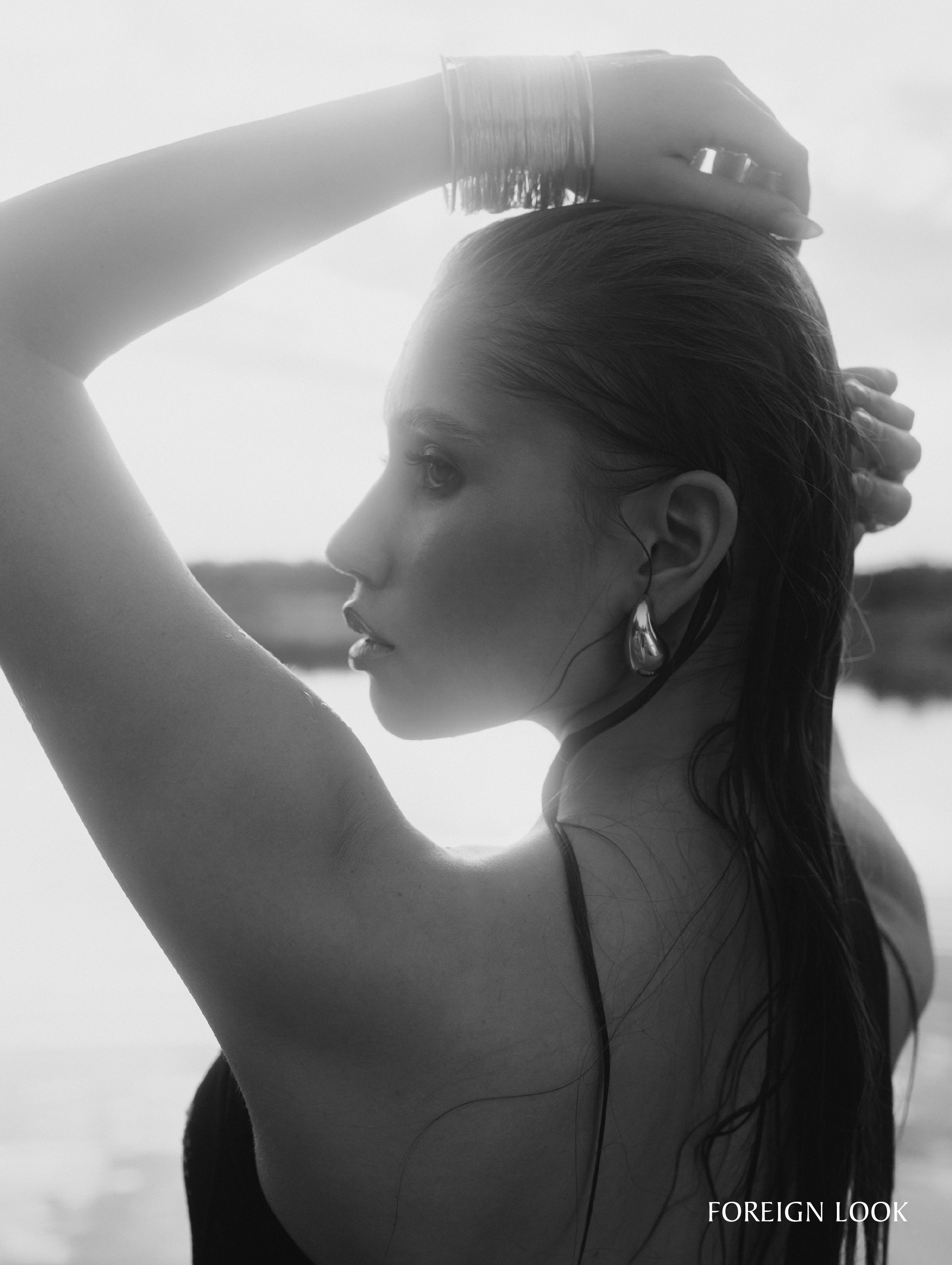 Портрет девушки с крупными серьгами в озере в контровом свете.