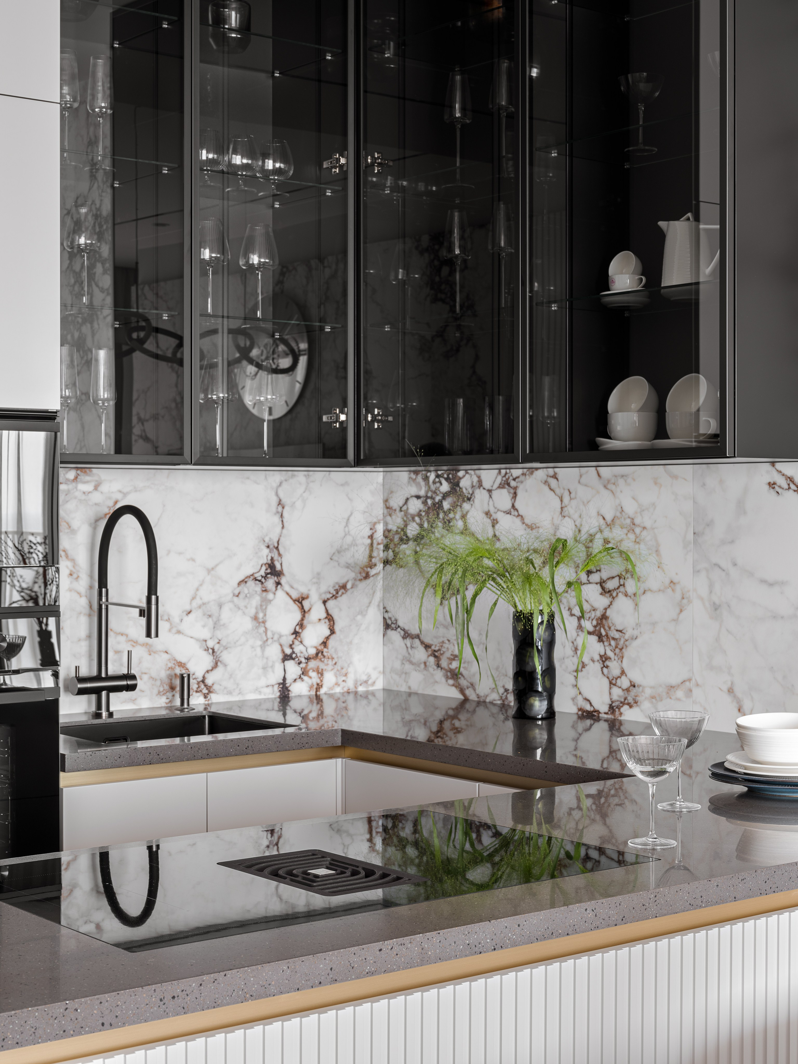 Деталь интерьера кухни в Сочи: рабочая поверхность из камня, черный смеситель, стеклянные шкафы для посуды и мраморный фартук. Элегантный проект дизайнеров Рената Байчукова и Алеcи Кириенко, стилизация Екатерины Ракитиной, съемка Сергея Денисенко.