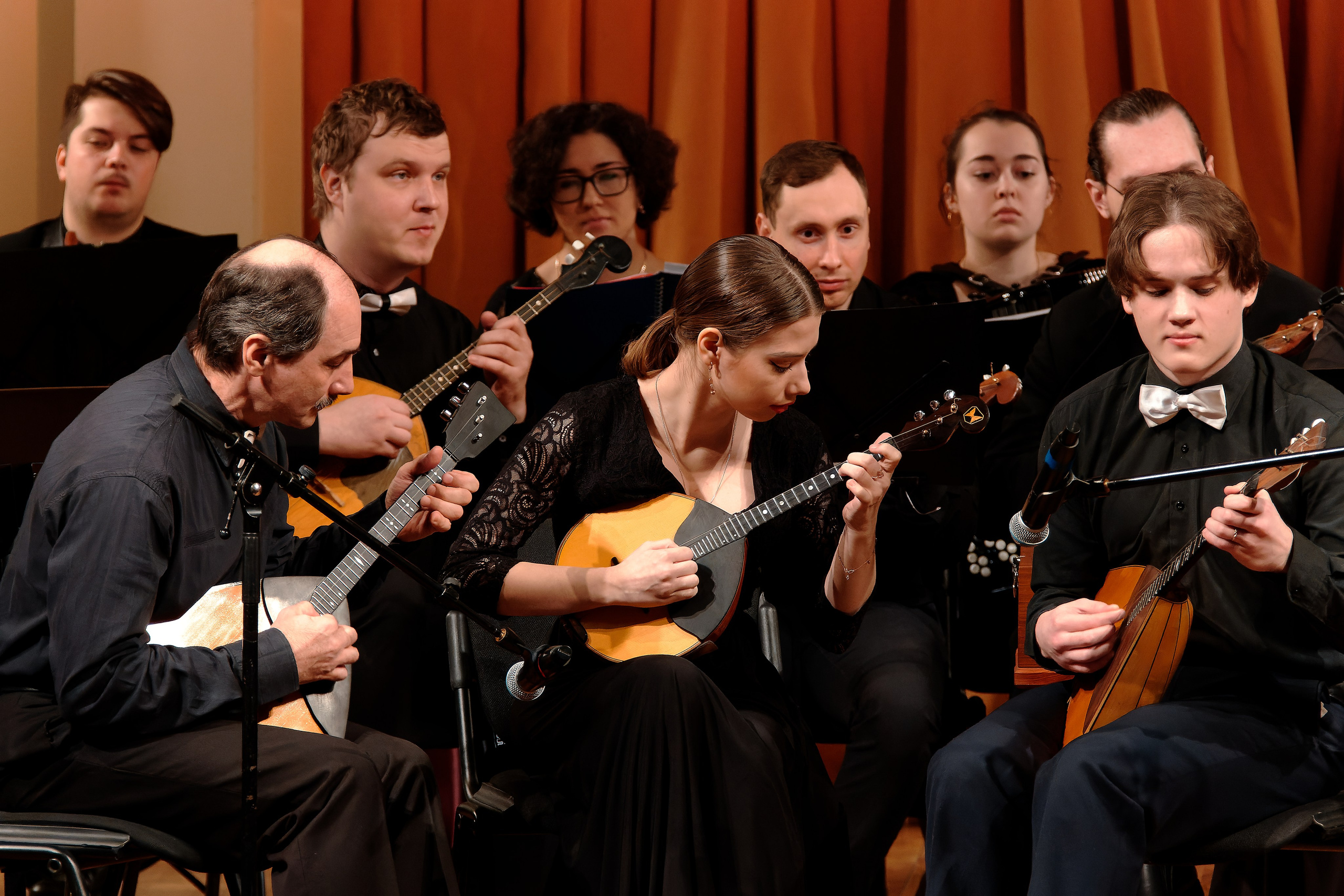 Ансамбль народных инструментов - музыканты играют на балалайках во время концерта, съемка выступления оркестра русских народных инструментов