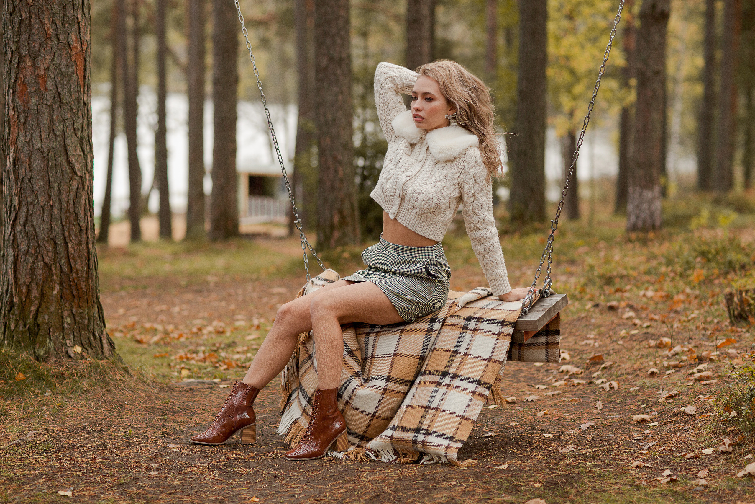 девушка сидит на качели на клетчатом пледе