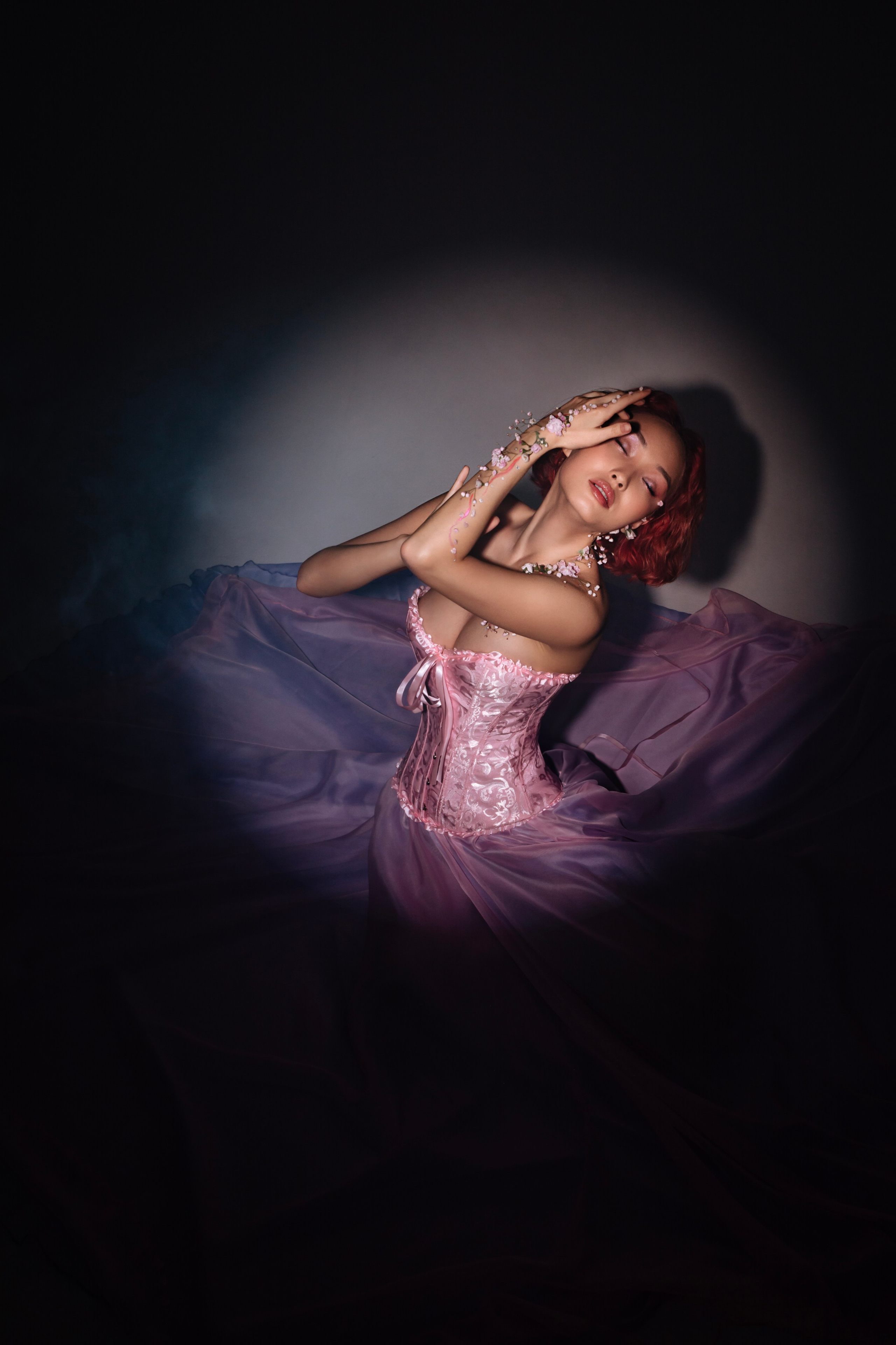 Окруженная ореолом света, хрупкая фигура девушки в розовом платье усыпана нежными цветами, олицетворяя собой возрождение природы после зимнего сна и наступление весны во всей ее красоте.