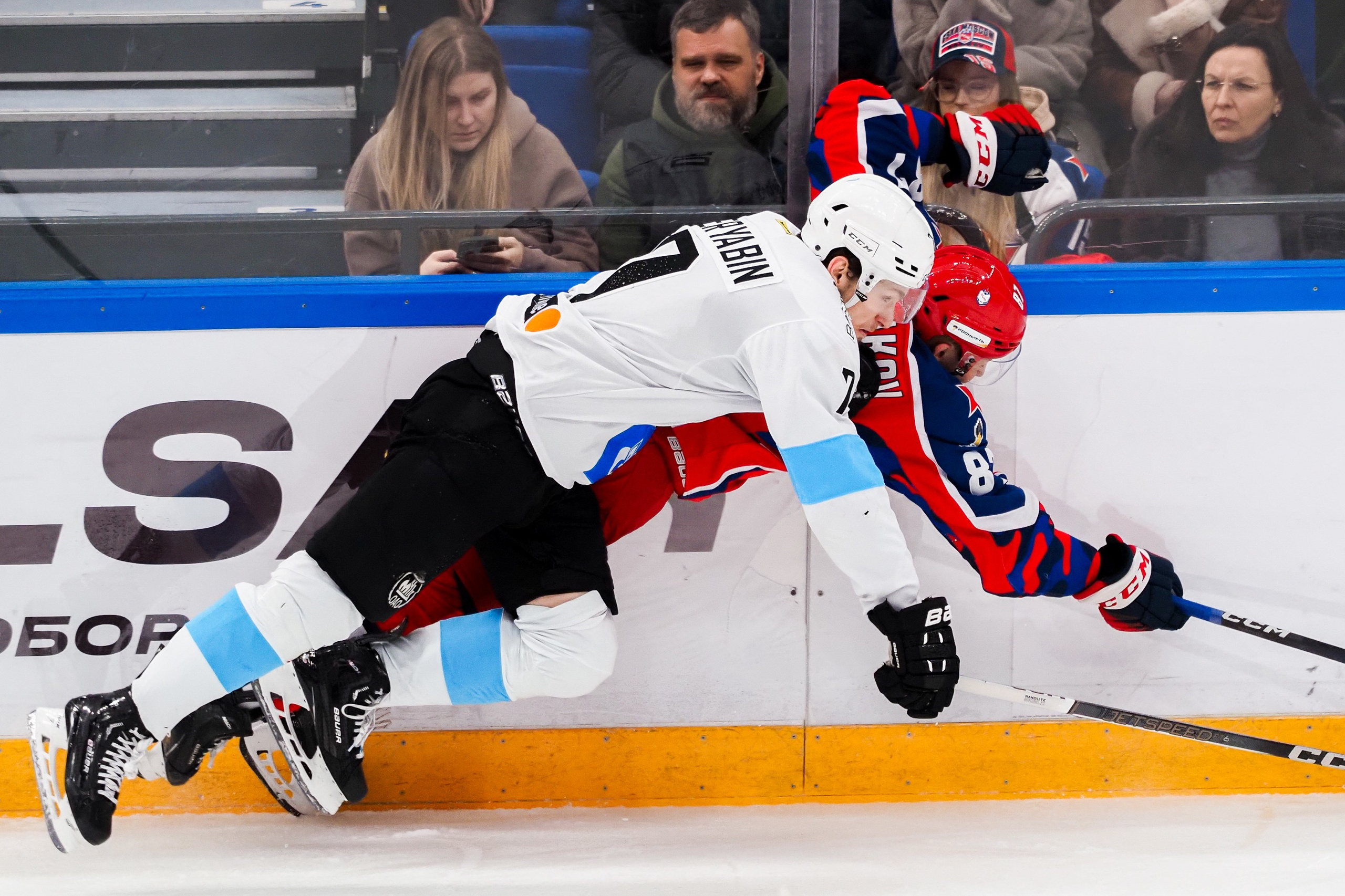 Двое хоккеистов синхронно падают в борьбе за шайбу