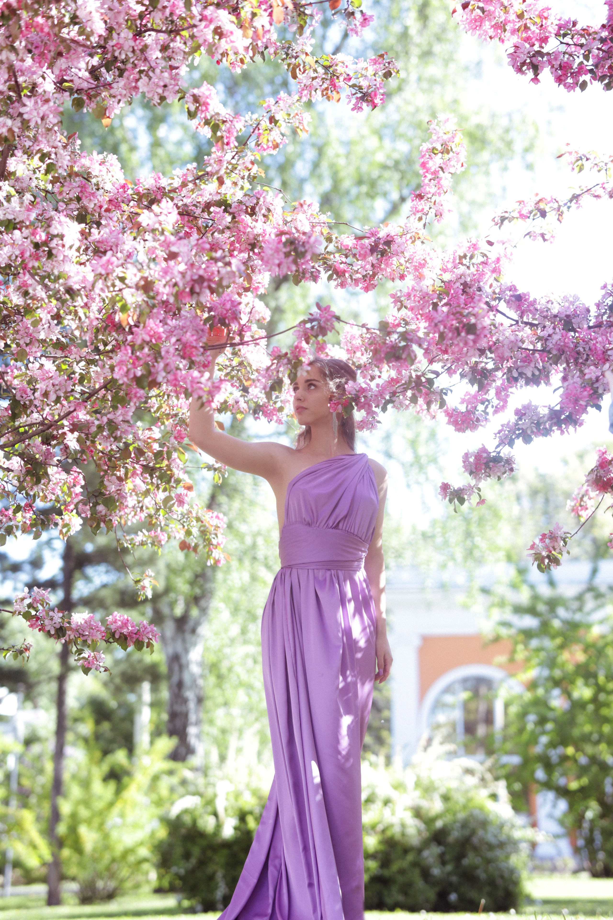 женщина в сиреневом платье на фоне цветущих деревьев
