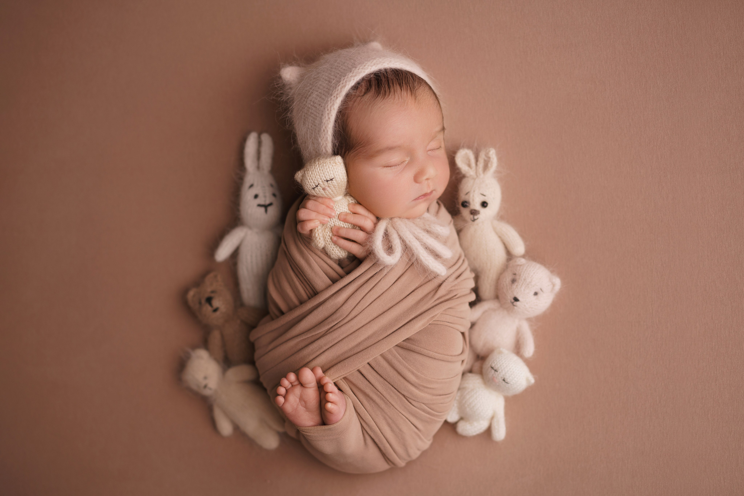 Малыш в коконе с игрушечным котиком и мелкими игрушками - съемка в стиле newborn