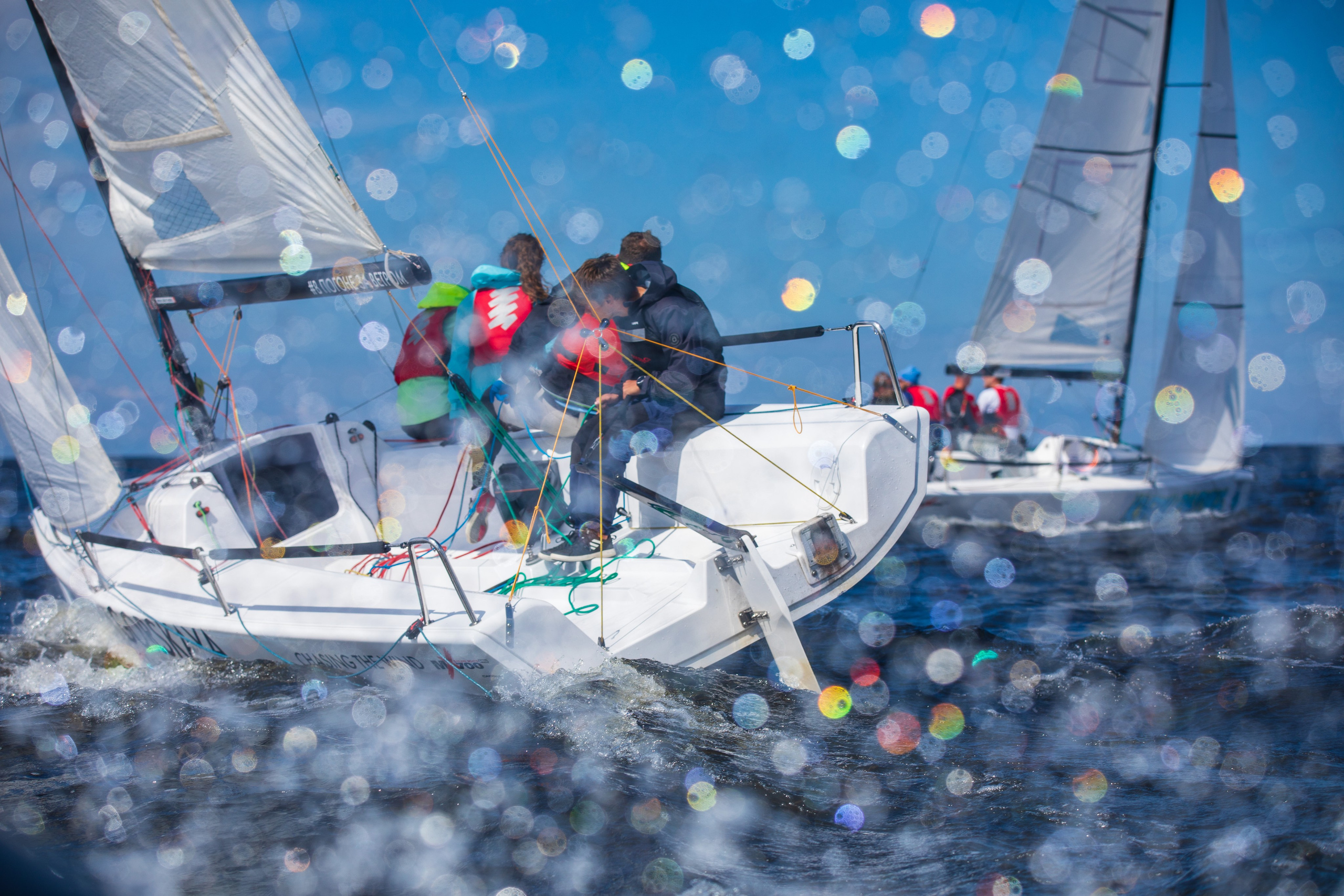 Капли воды в расфокусе на первом плане. Борьба спортсменов на гоночной дистанции.