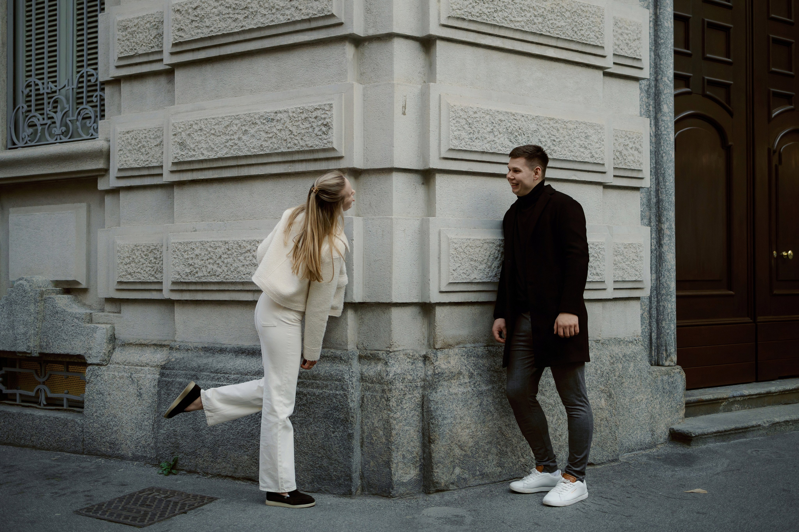 Пара у стены здания, минимализм и симметрия в кадре