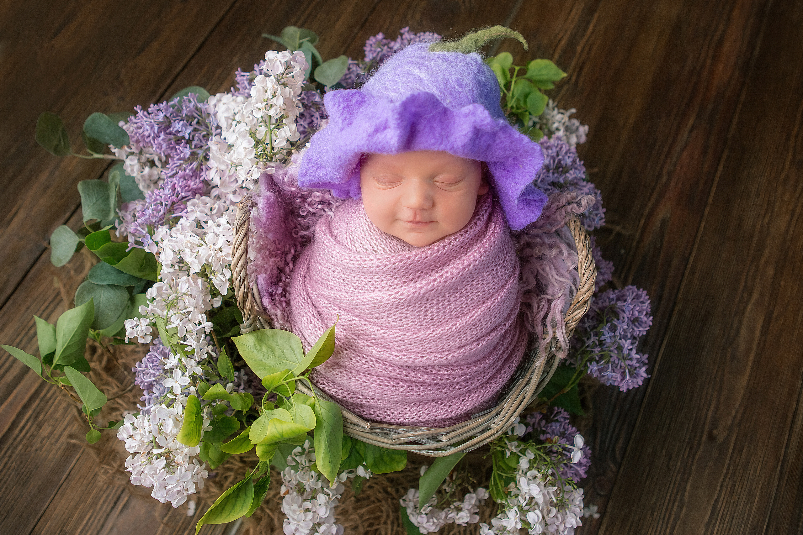 новорожденный малыш в шапочке-цветочек в корзине