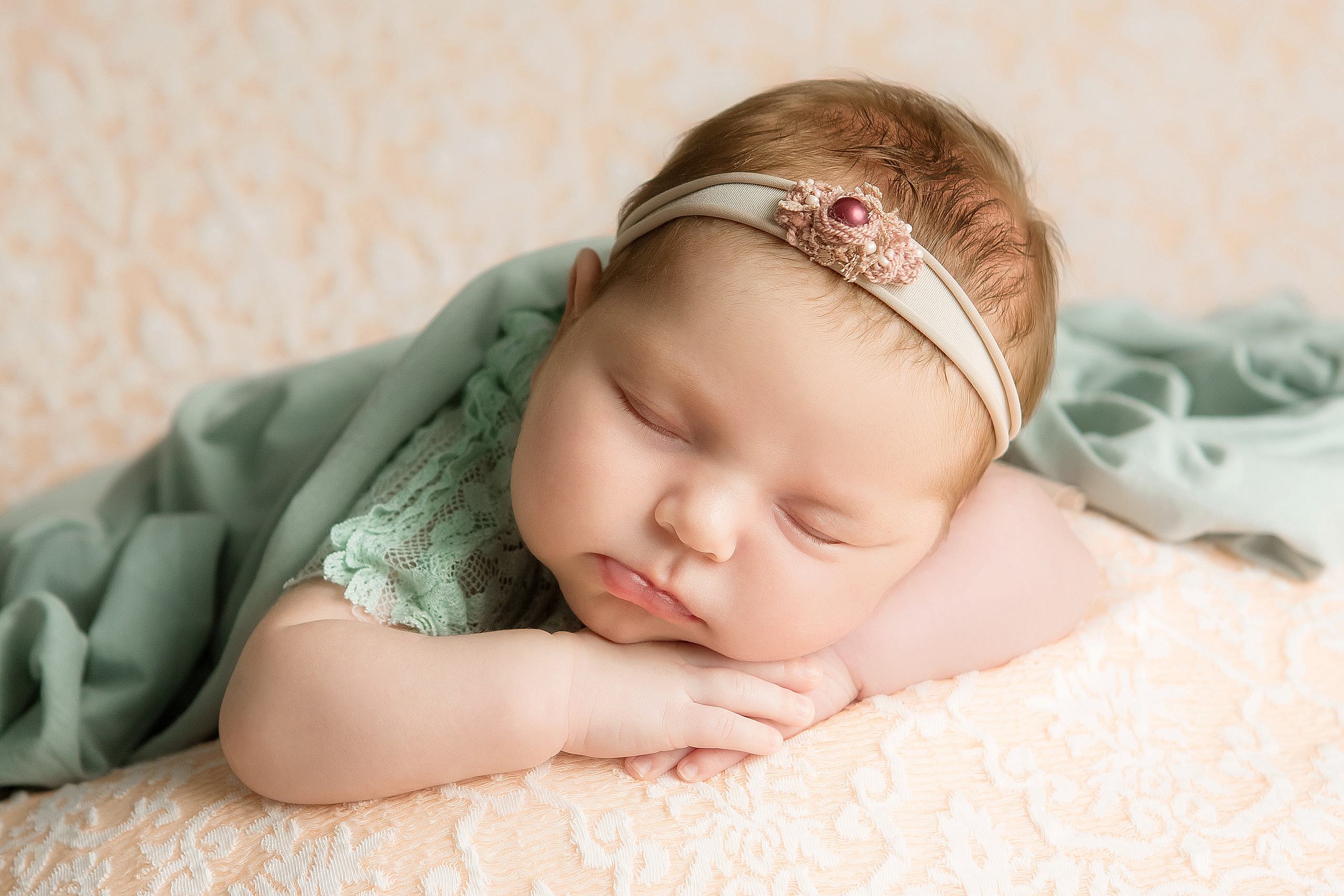 новорожденный малыш позировка на животике на подушке ручки под подбородком в ободочке