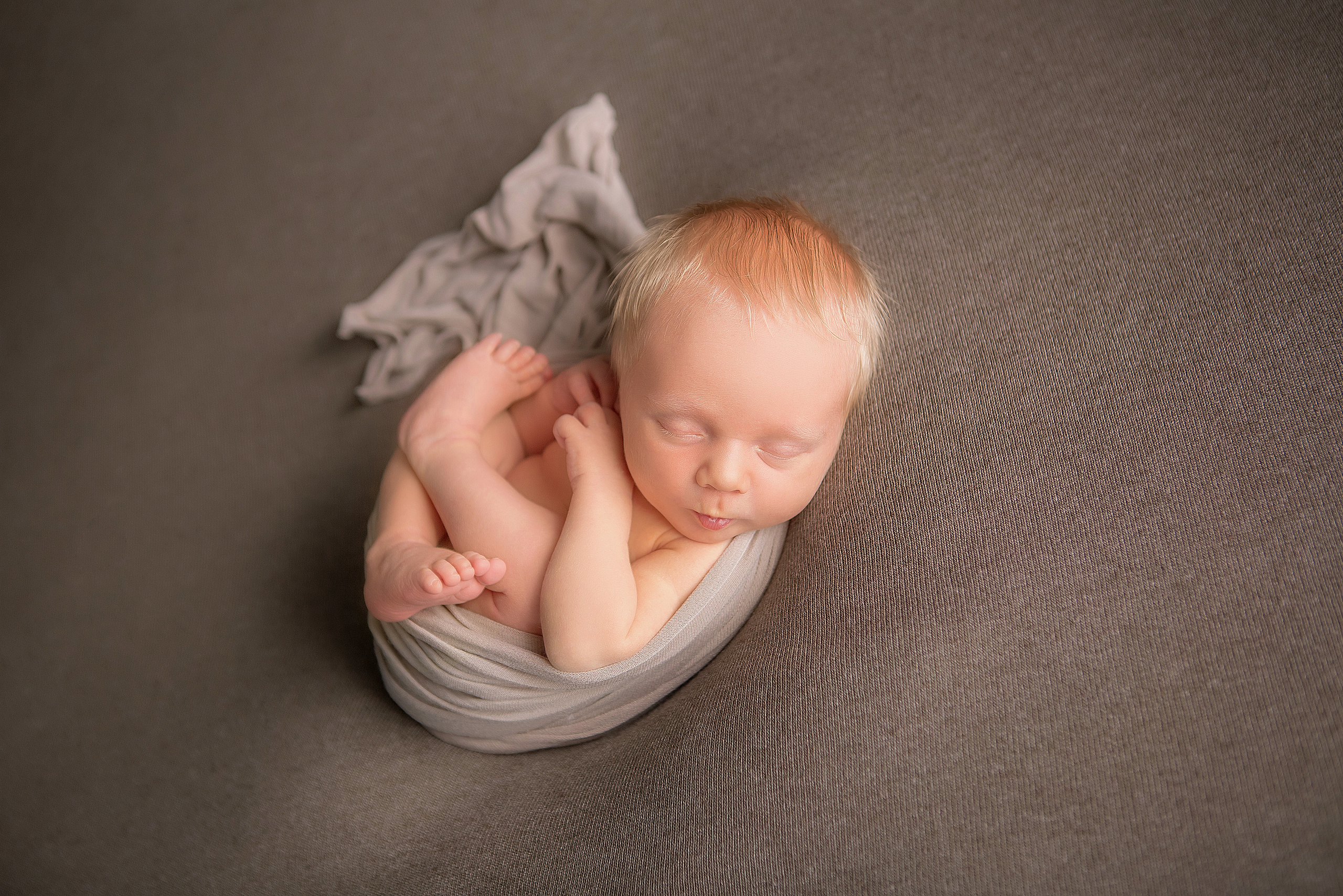 новорожденный малыш в серой обмотке ножки сложены бабочкой