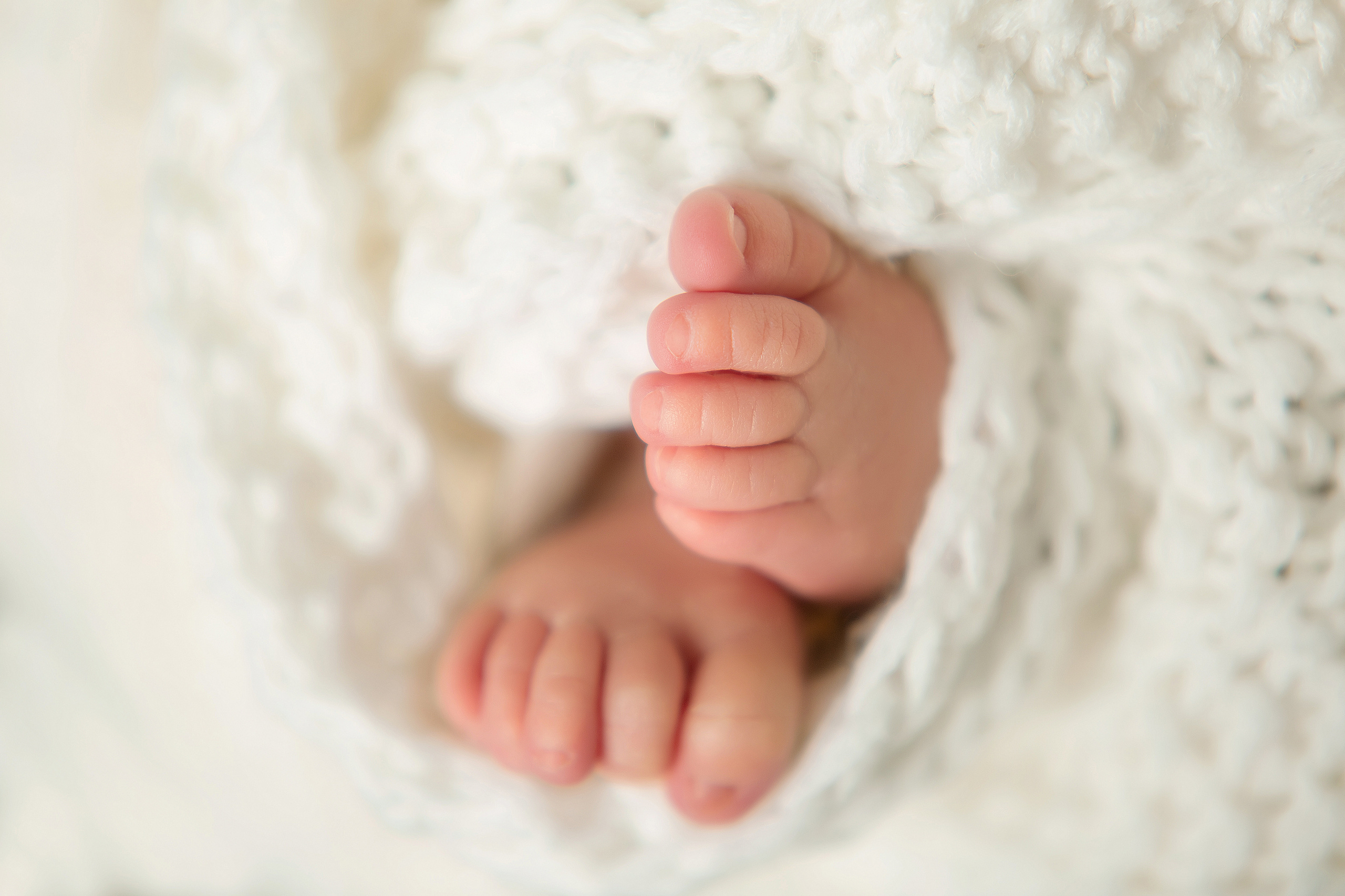 ножки новорожденного малыша укутанные в белый шарф