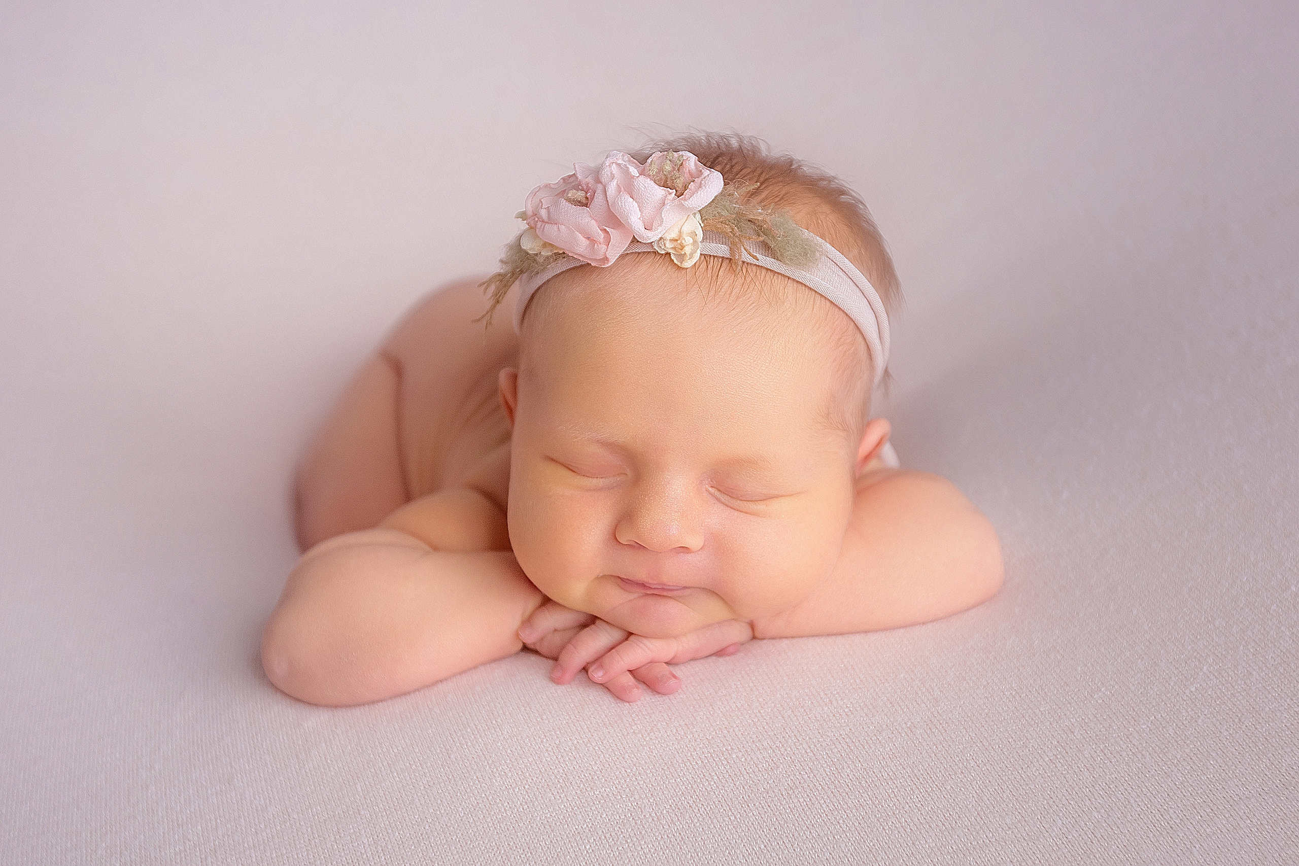 новорожденный малыш позировка на животике на подушке ручки под подбородком в ободочке