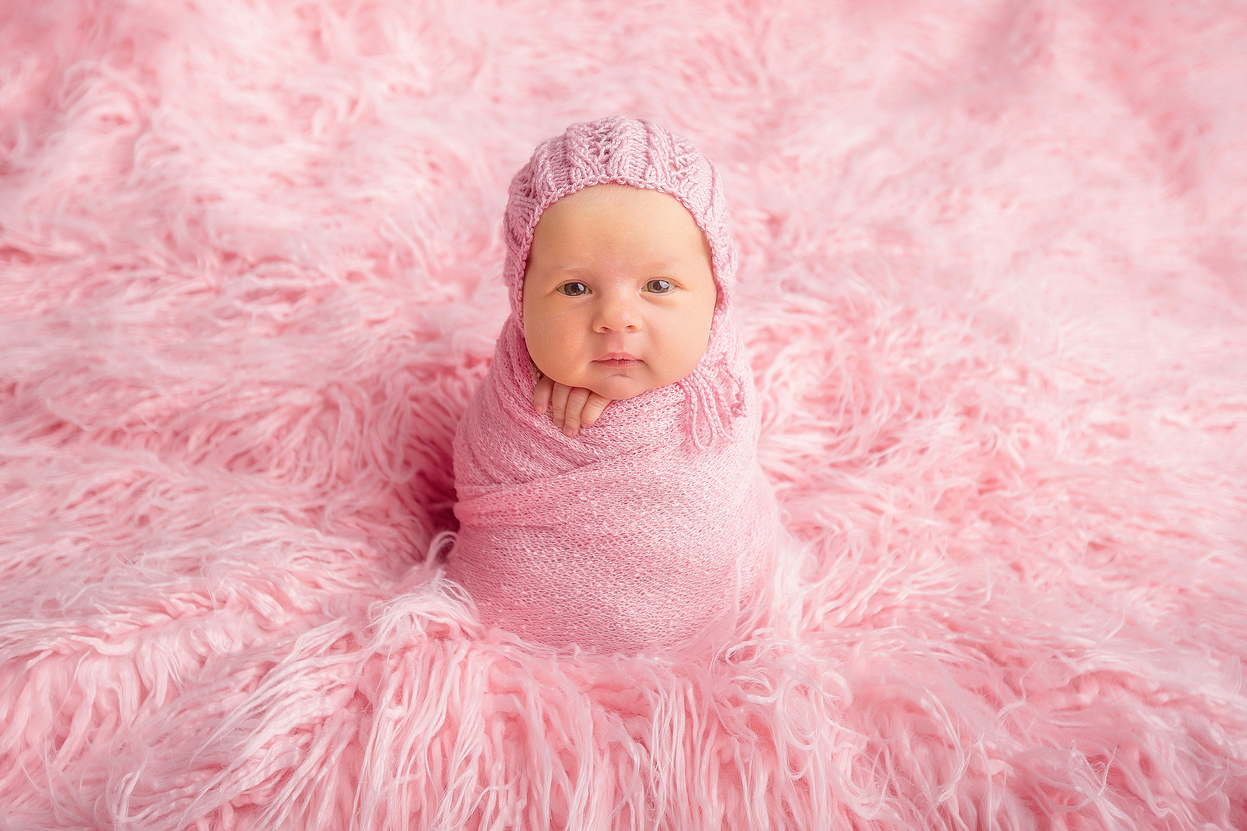 новорожденная малышка на нежно-розовом фоне