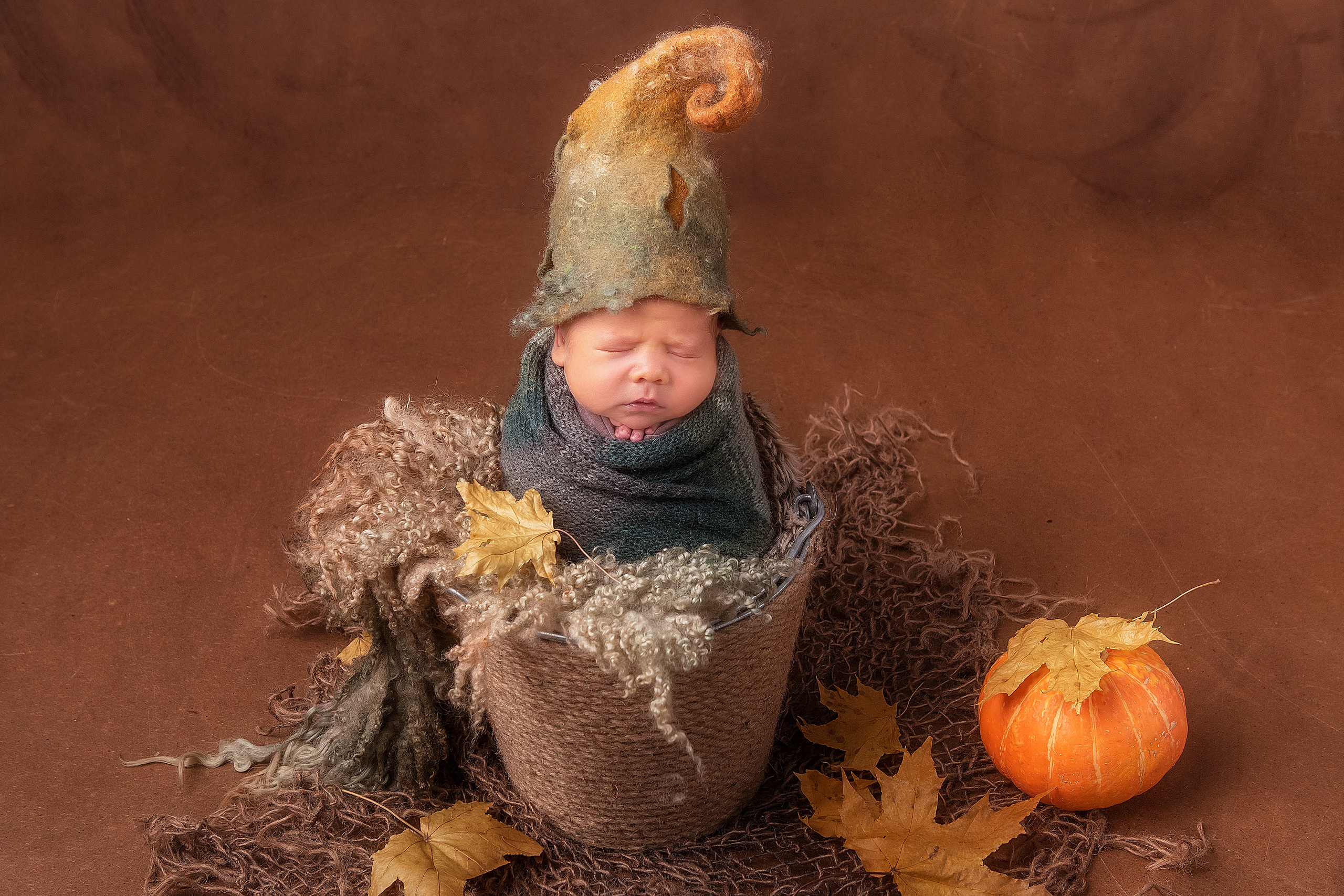 новорожденный малыш в ведерке и колпаке с тыквой. хэллоуин