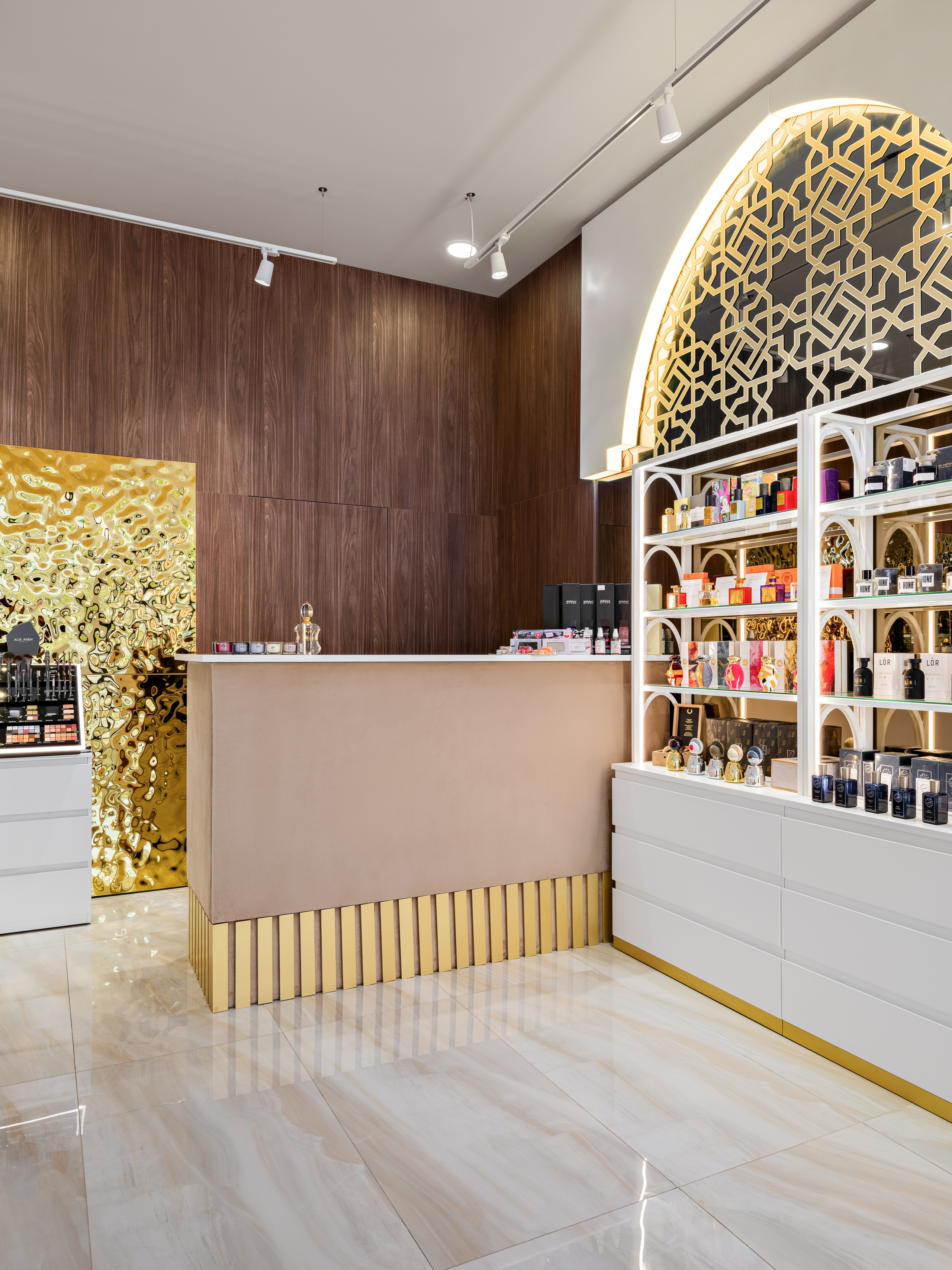 Интерьер кассовой зоны парфюмерного бутика с золотыми акцентами, деревянными панелями и стильной стойкой. Восточные арки с подсветкой украшают витрины, дизайнер Мария Никишина, фотограф Сергей Денисенко.