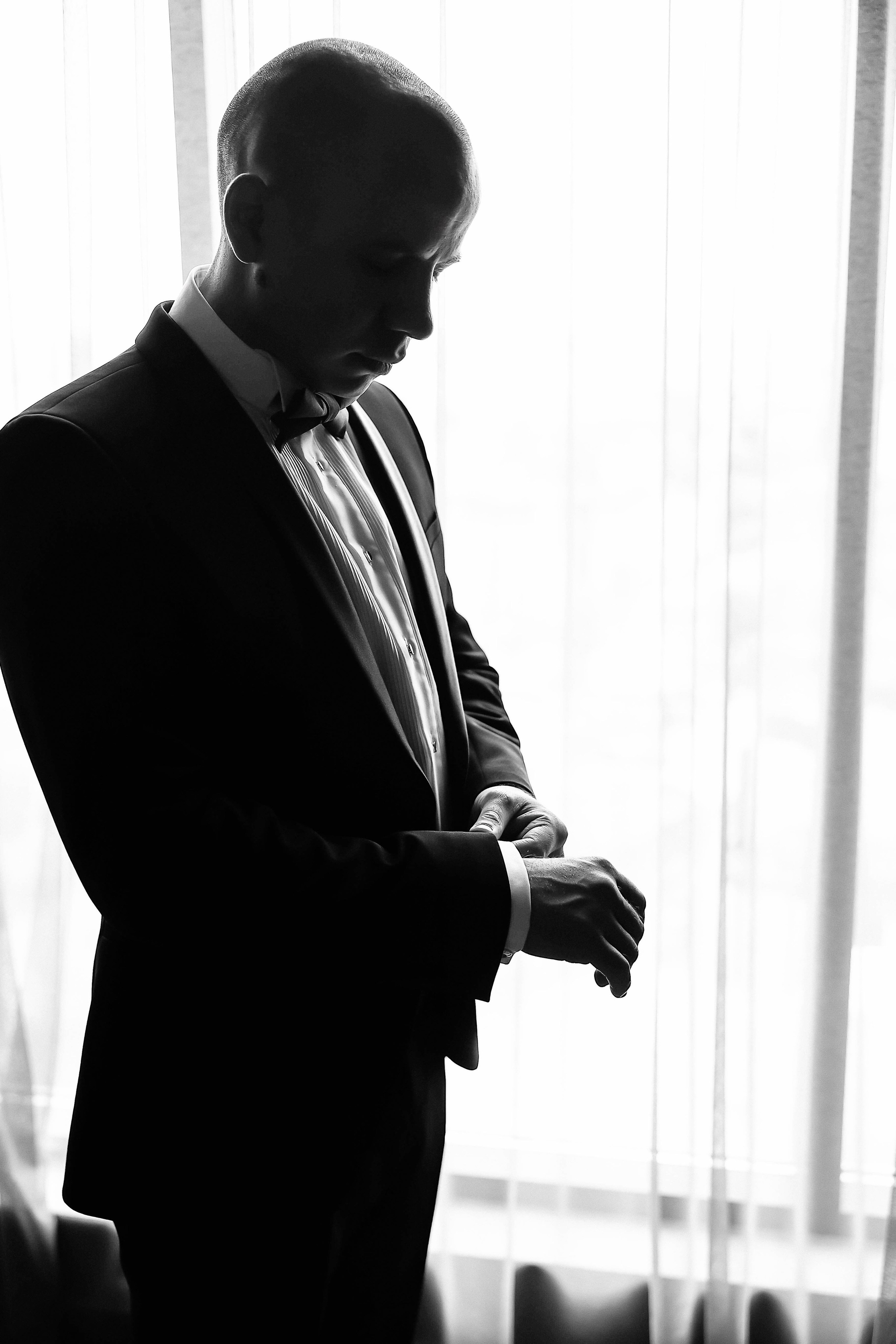 Жених поправляет запонки, свадьба в интерьере на фотосессии