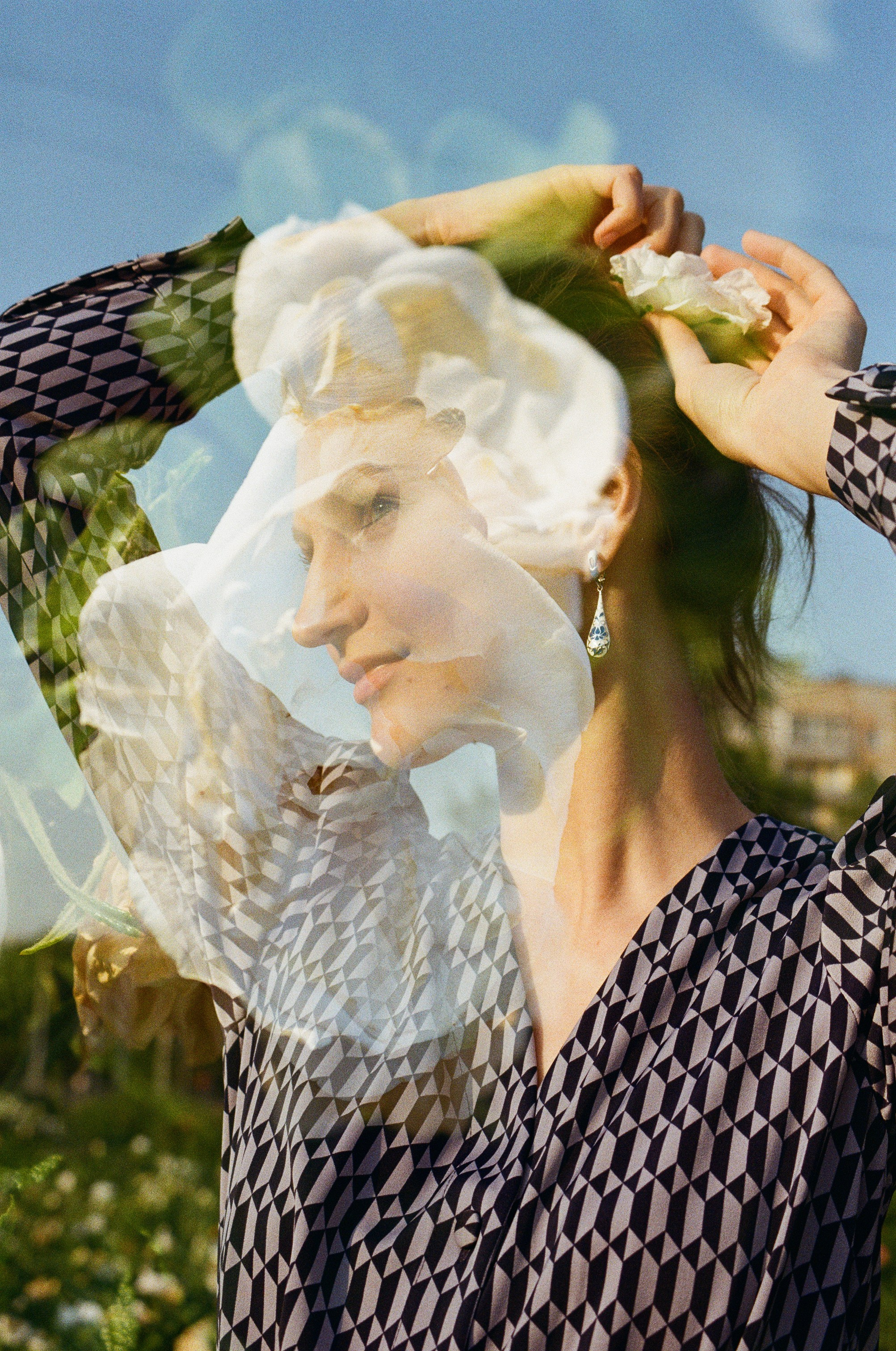 Портрет красивой девушки в лучах вечернего солнца с мультиэкспозицией на фоне белого шиповника