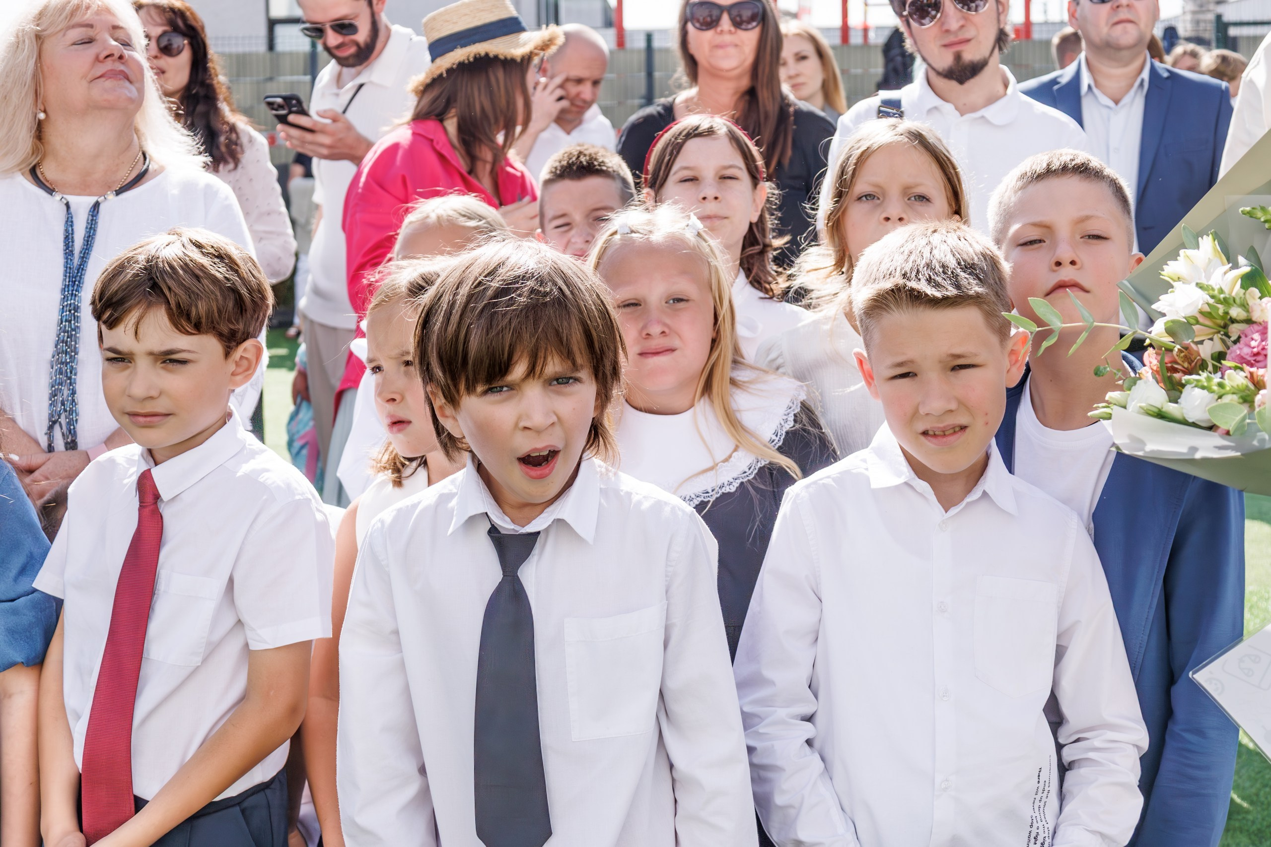 Линейка 1 сентября в школе - дети с букетами, радостные родители и учителя; дети обнимаются, радуются встрече с друзьями после каникул