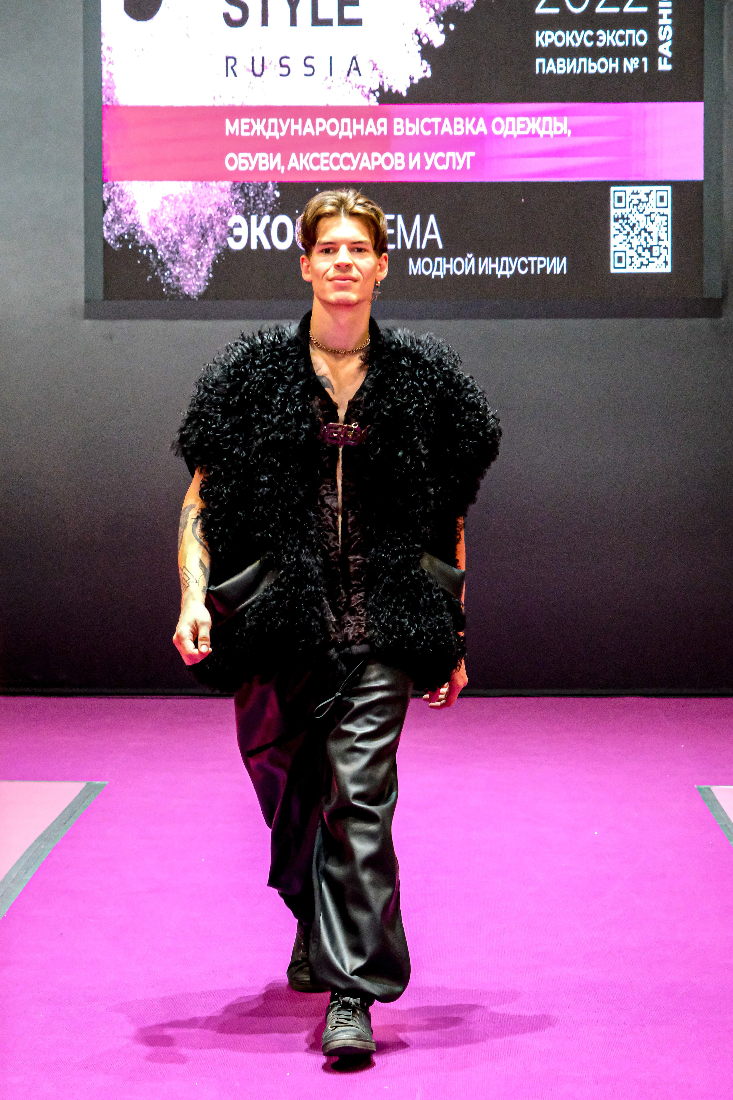  "Модели в ярких нарядах проходят по подиуму во время показа мод, освещенные яркими софитами и окруженные восторженными зрителями."