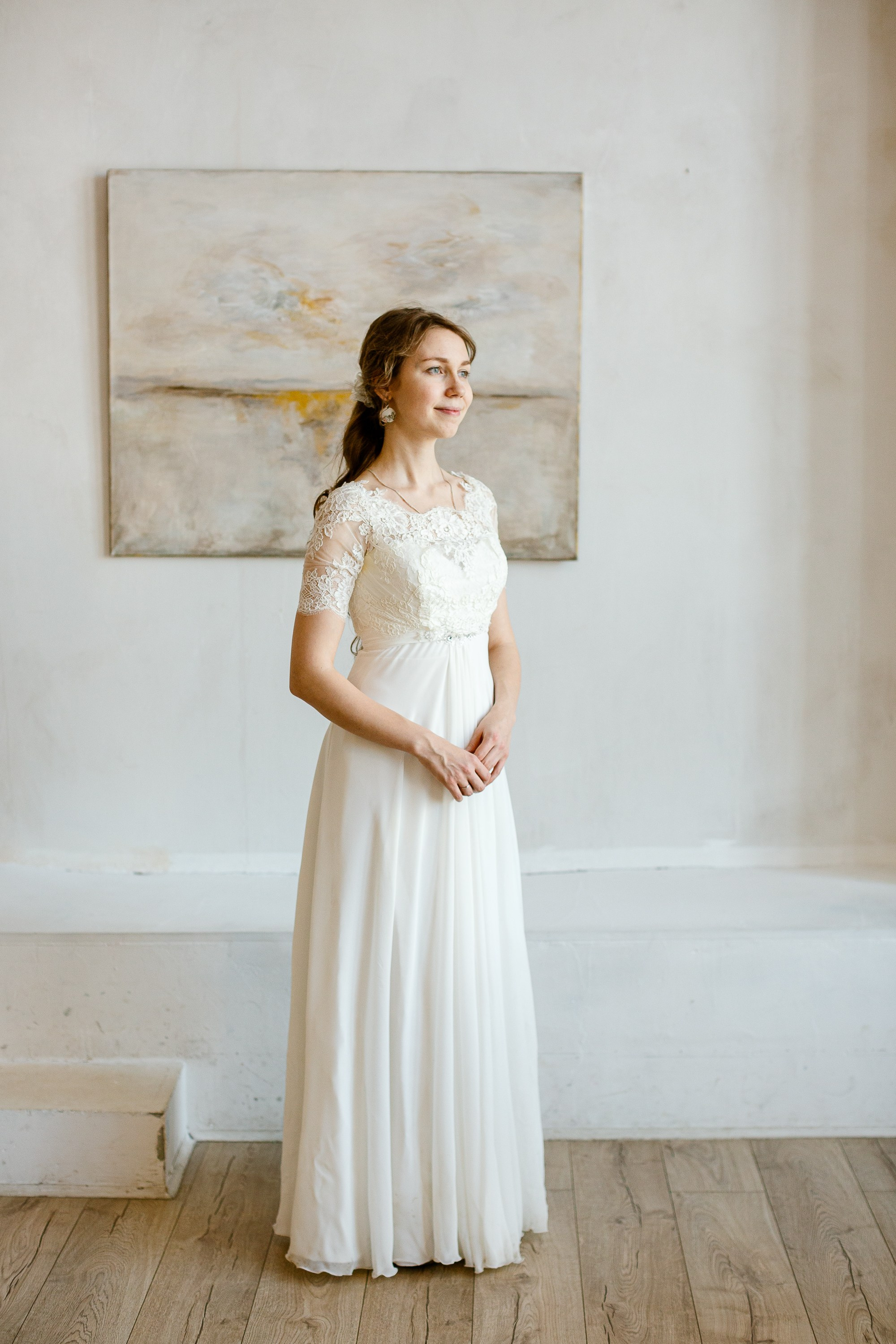 Невеста в красивом белом платье. На фоне картина.