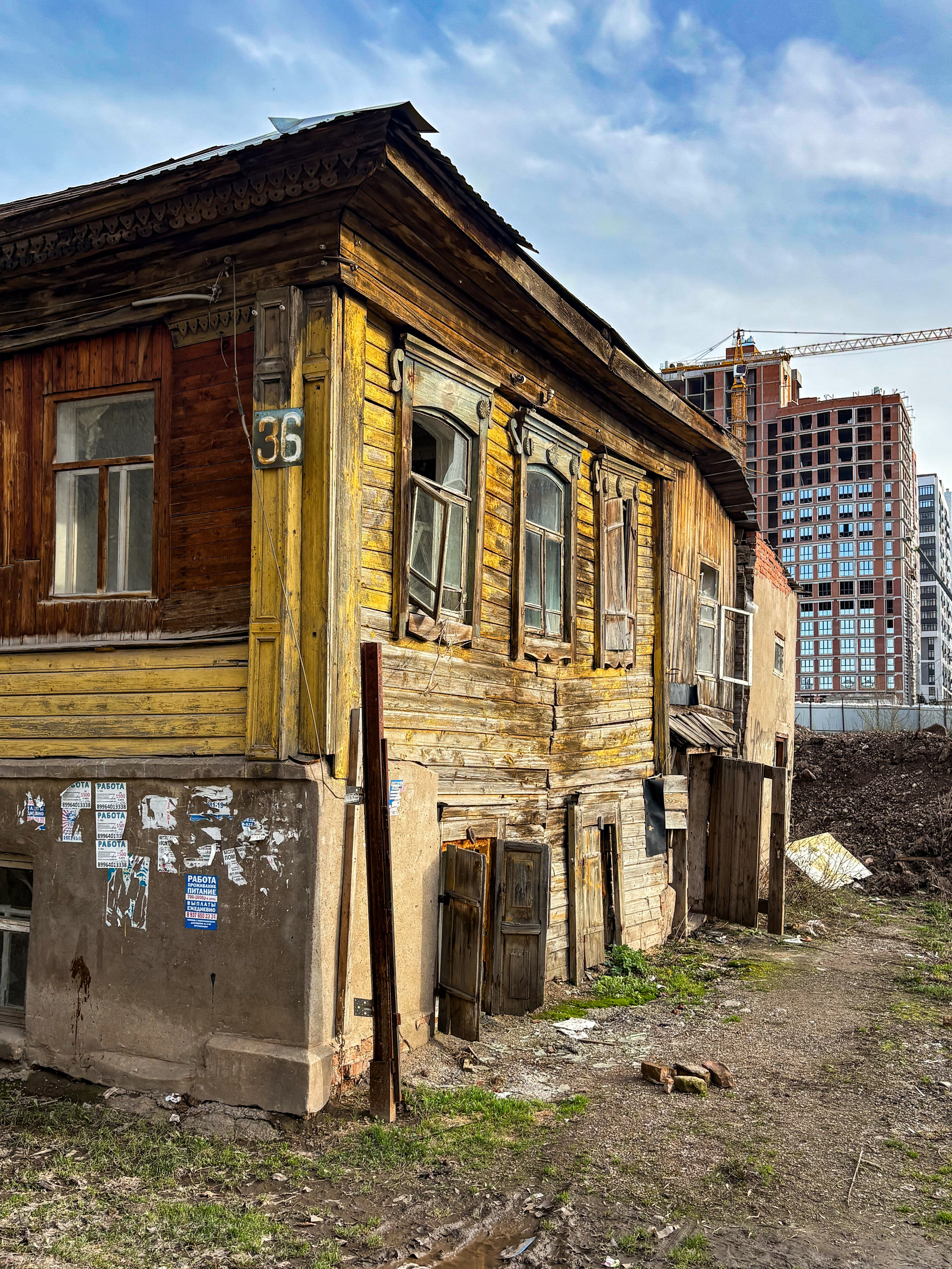 Старый деревянный дом на фоне строящейся многоэтажки