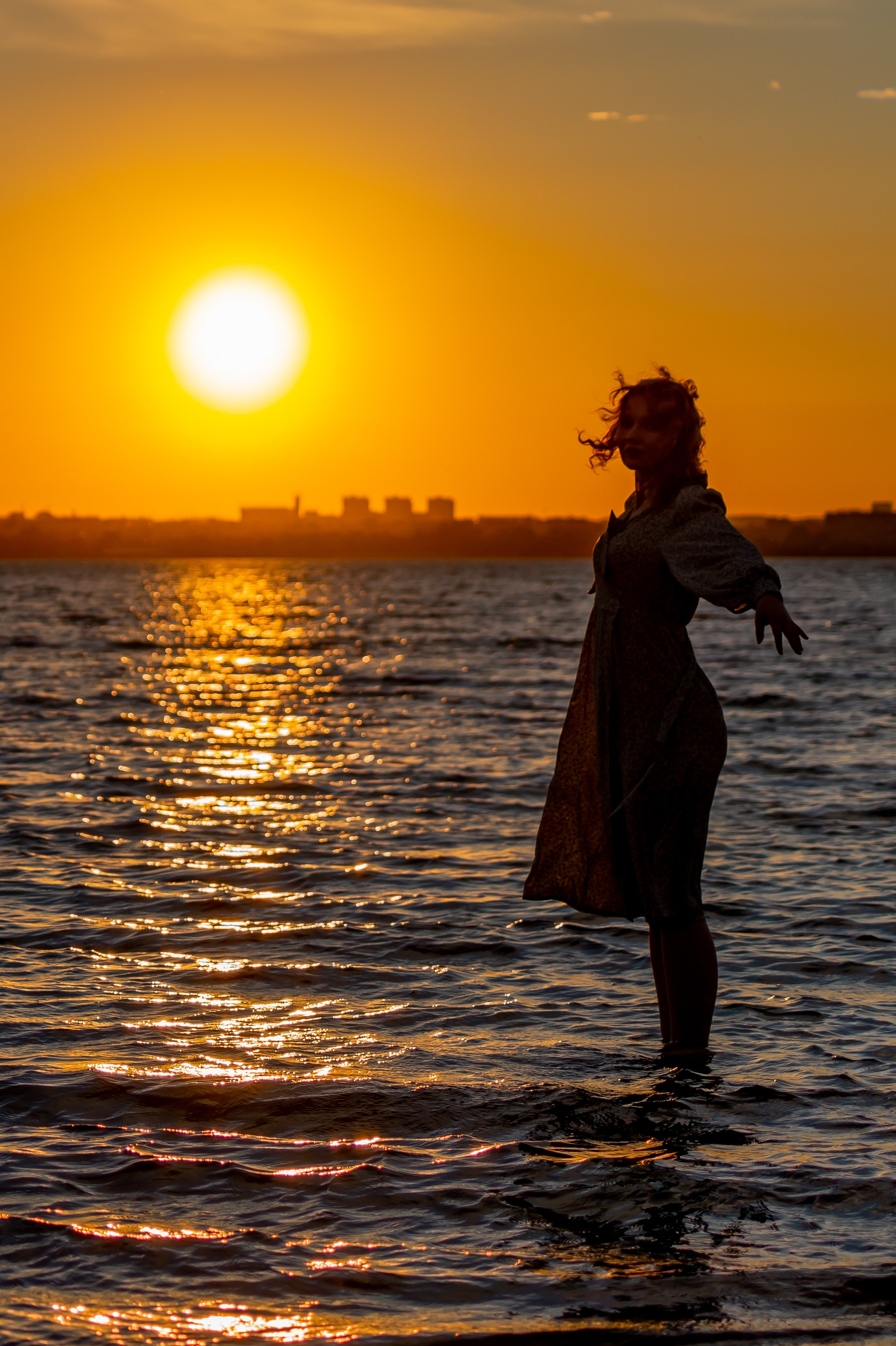Силуэт девушки на берегу моря при закате. Красивая фотография в золотых тонах