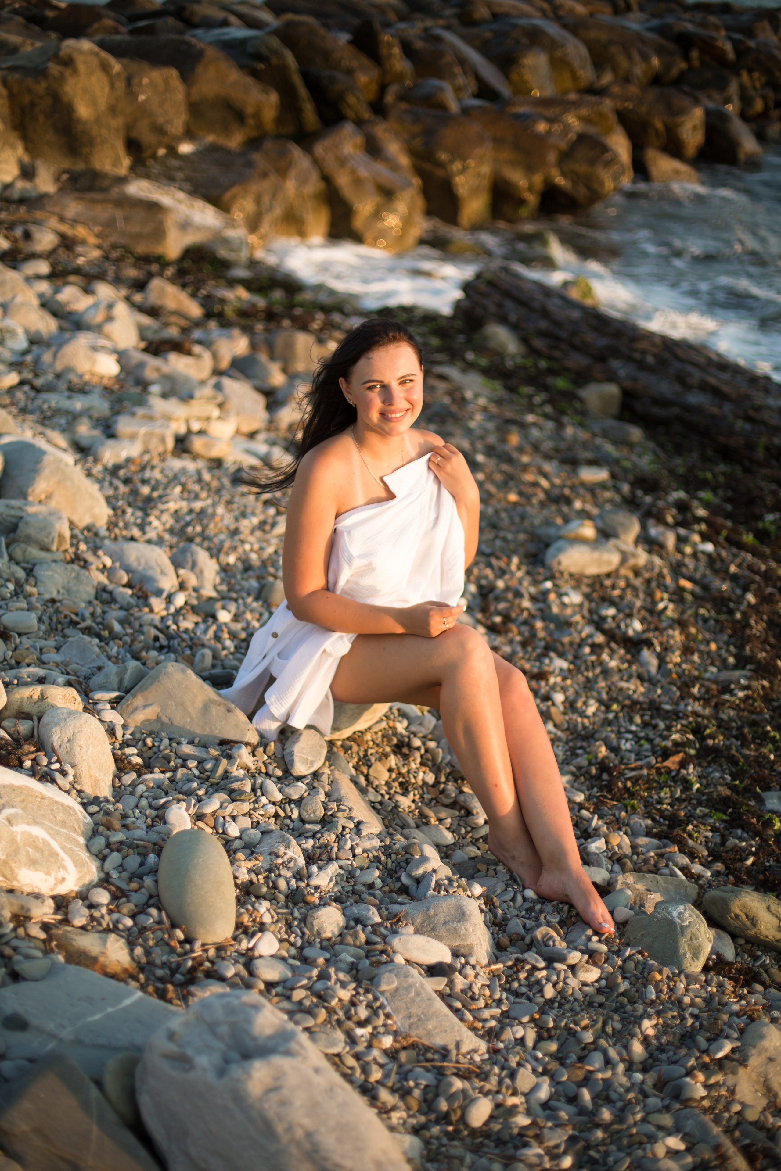 женщина сидит на каменистом пляже