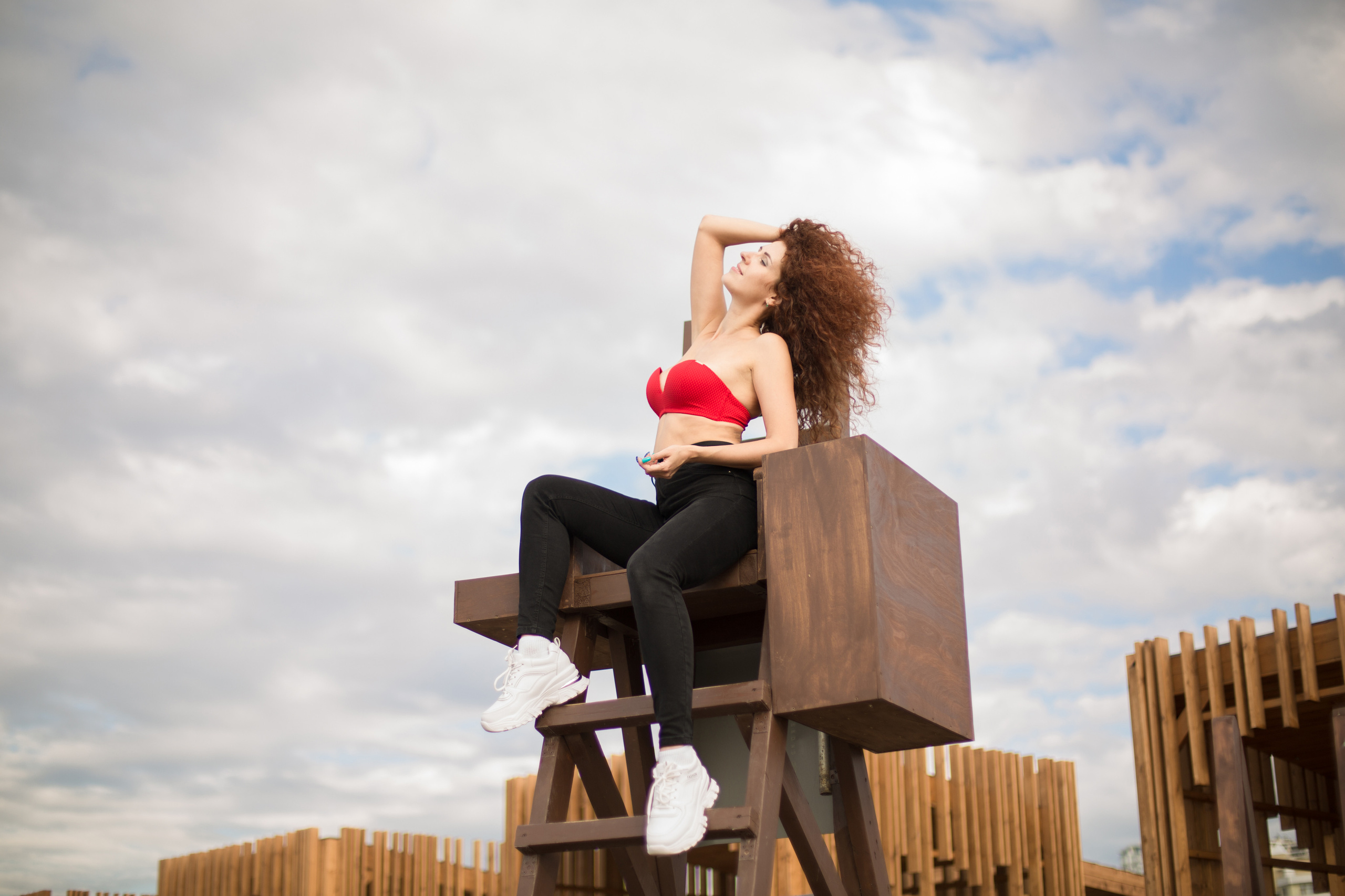 Девушка сидит на фоне неба и облаков