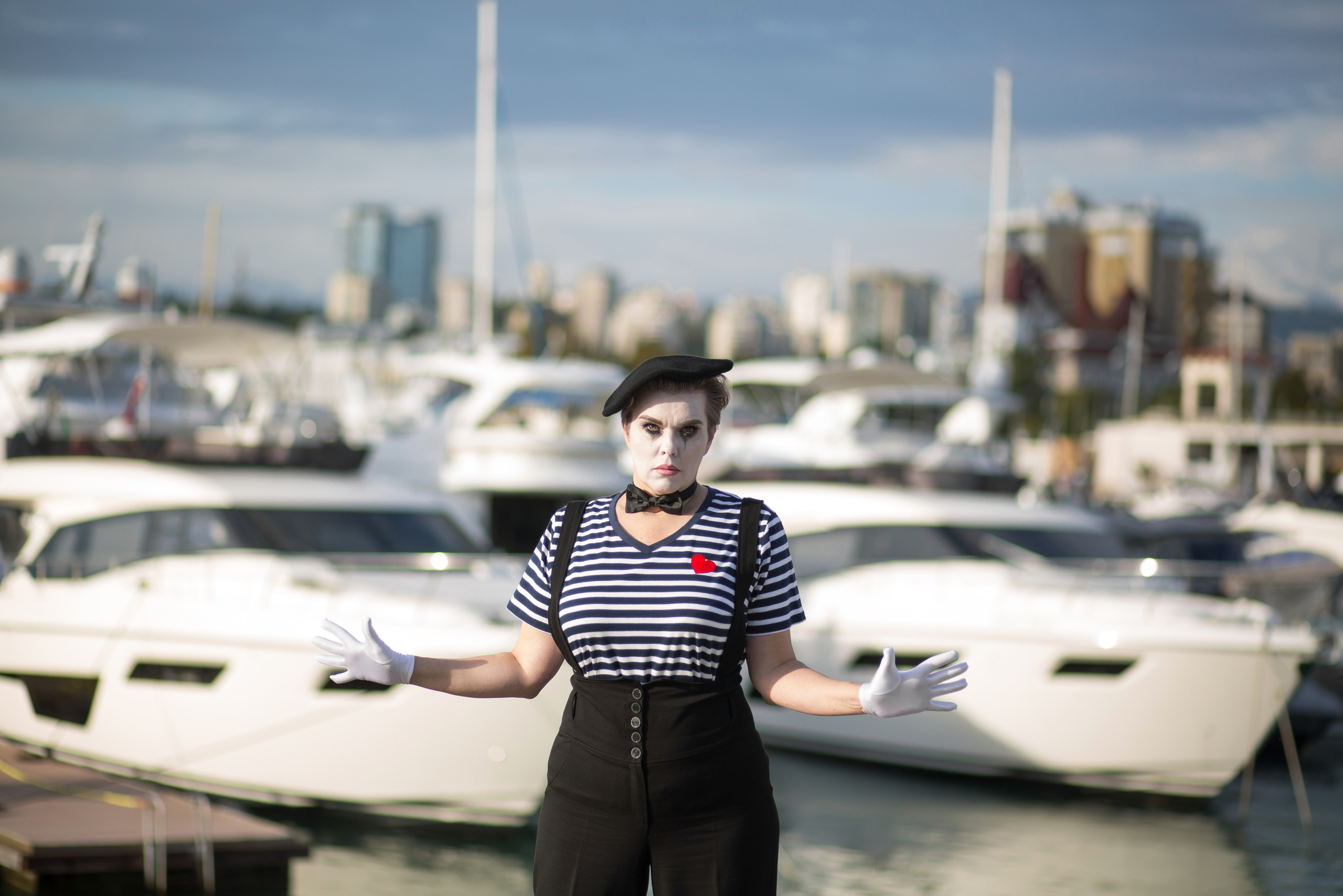 Мим разводит руки на фоне яхт