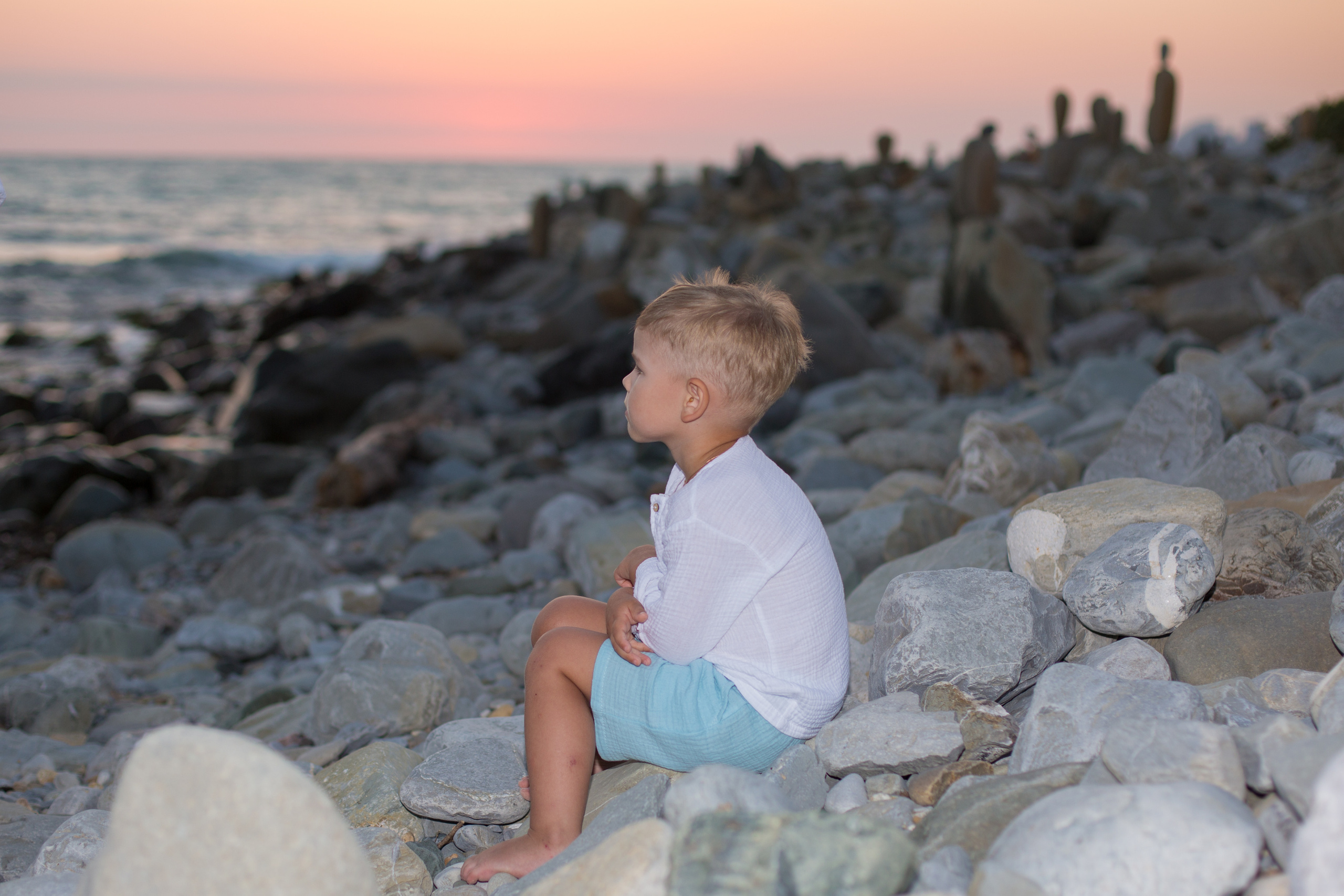 мальчик сидит на закате у моря