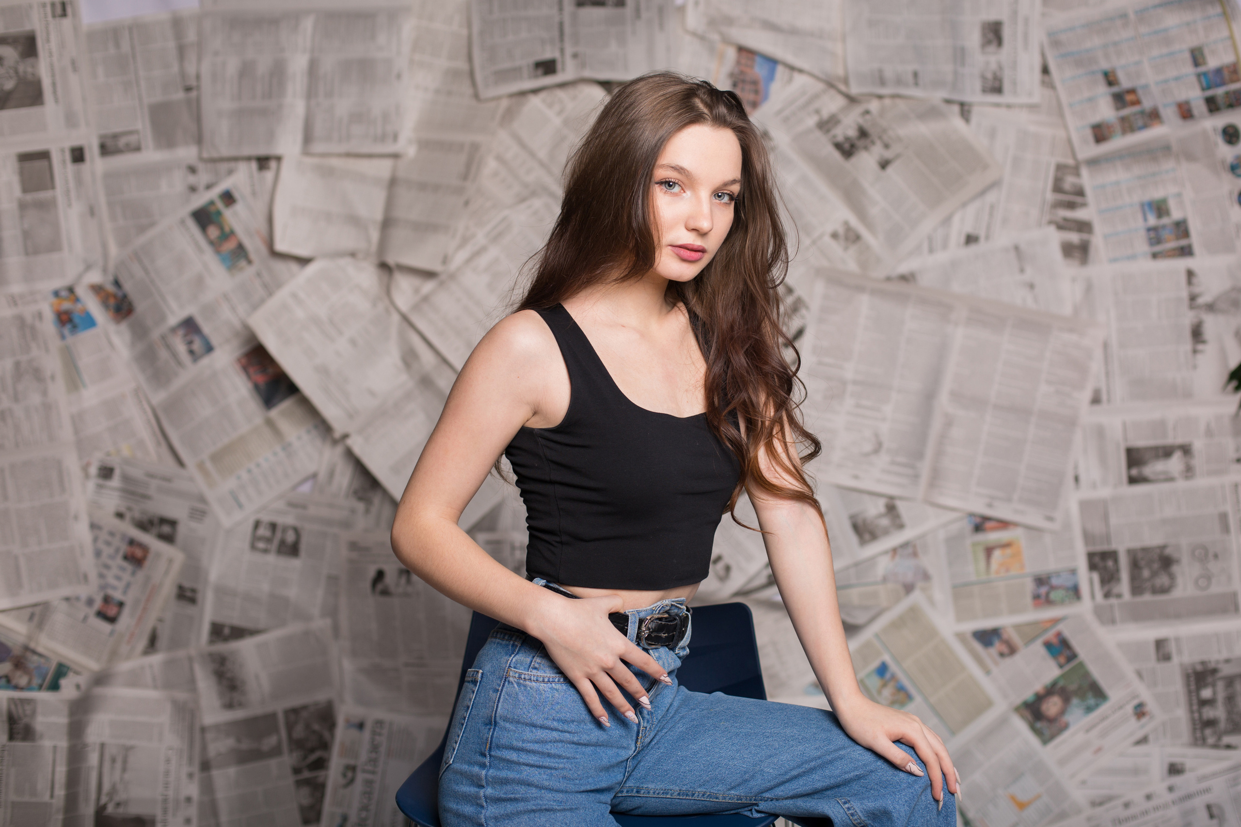 портрет девушки в джинсах  на фоне газет