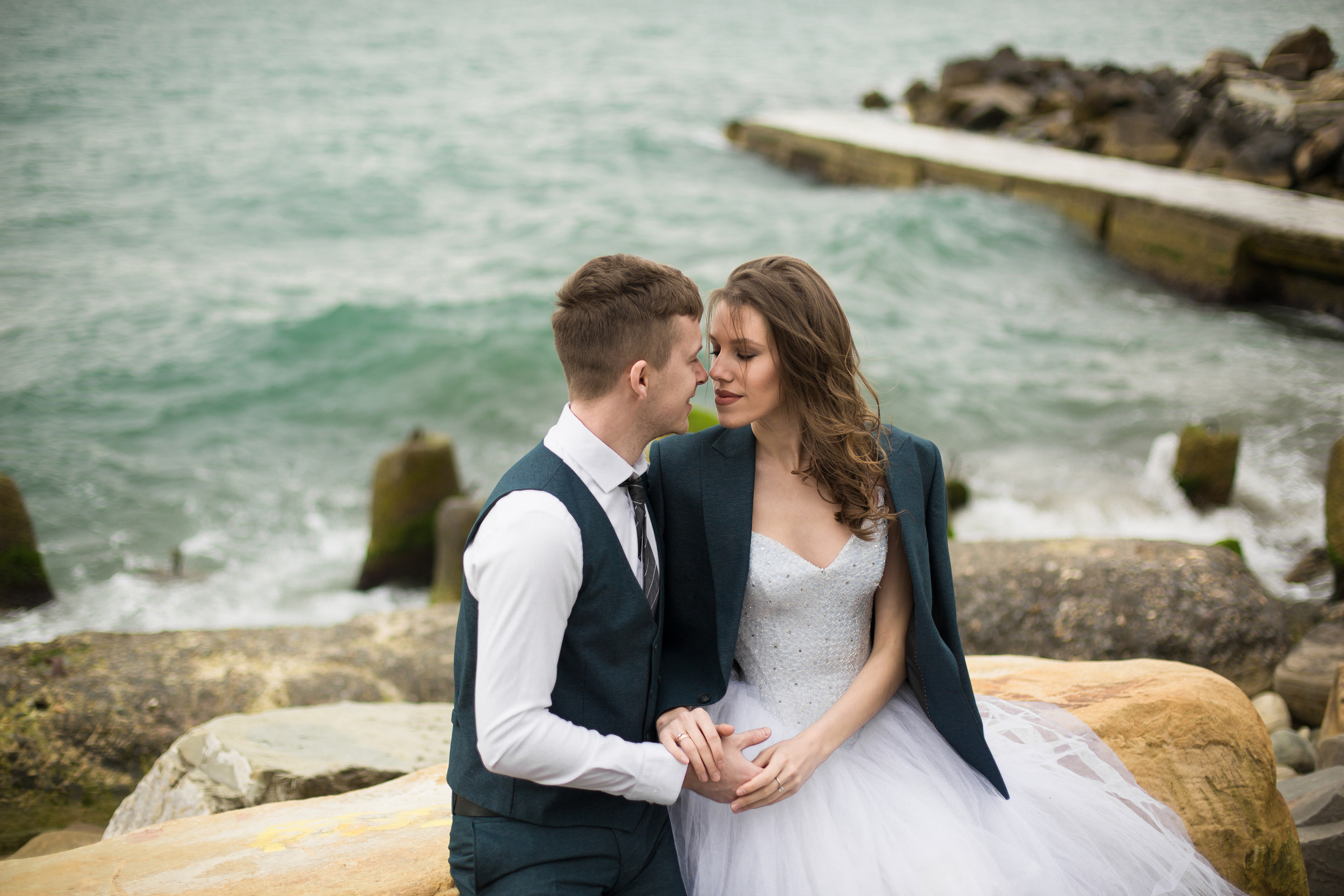 жених накинул пиджак невесте на фоне штормового моря