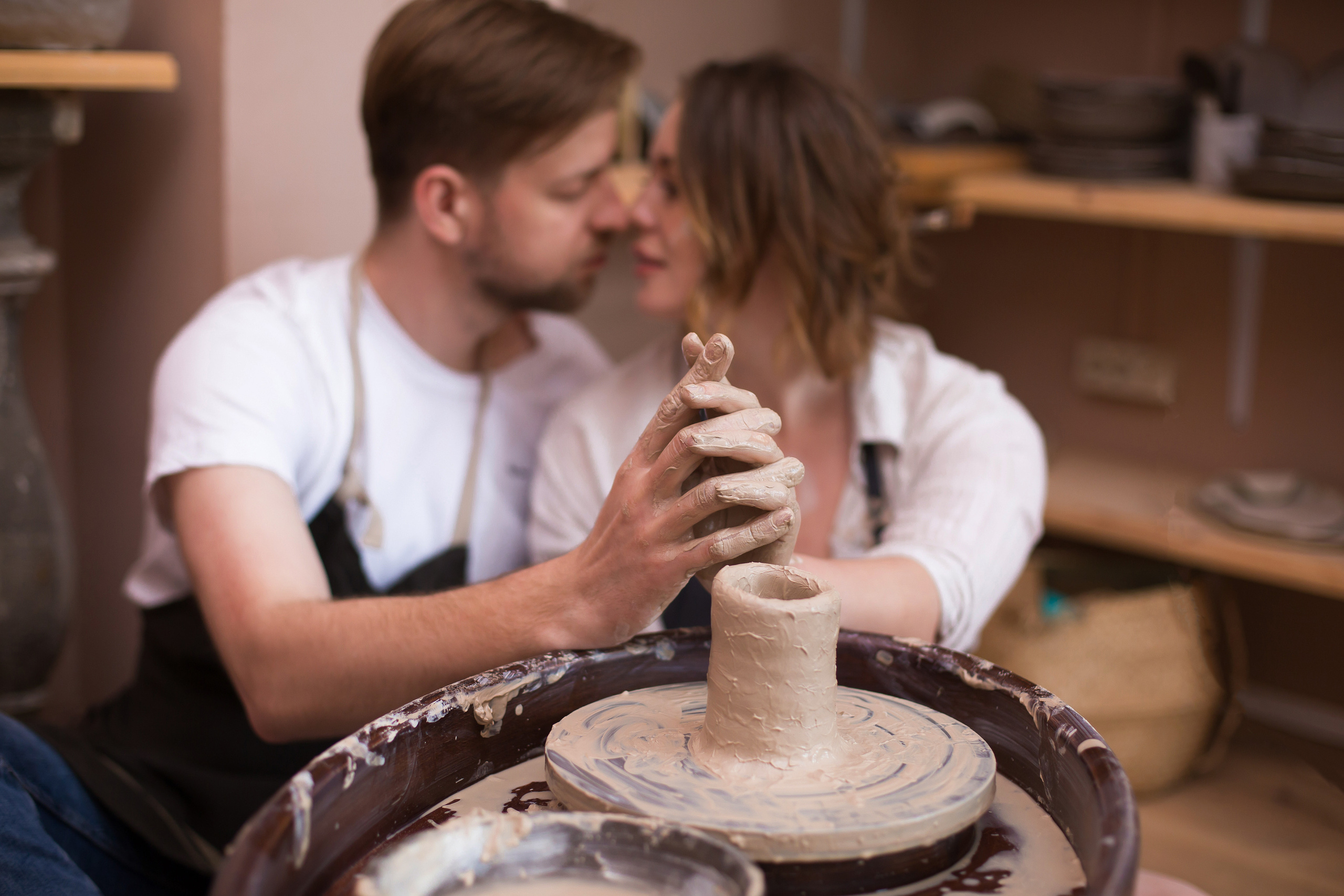 парень и девушка целуются на фоне гончарного круга