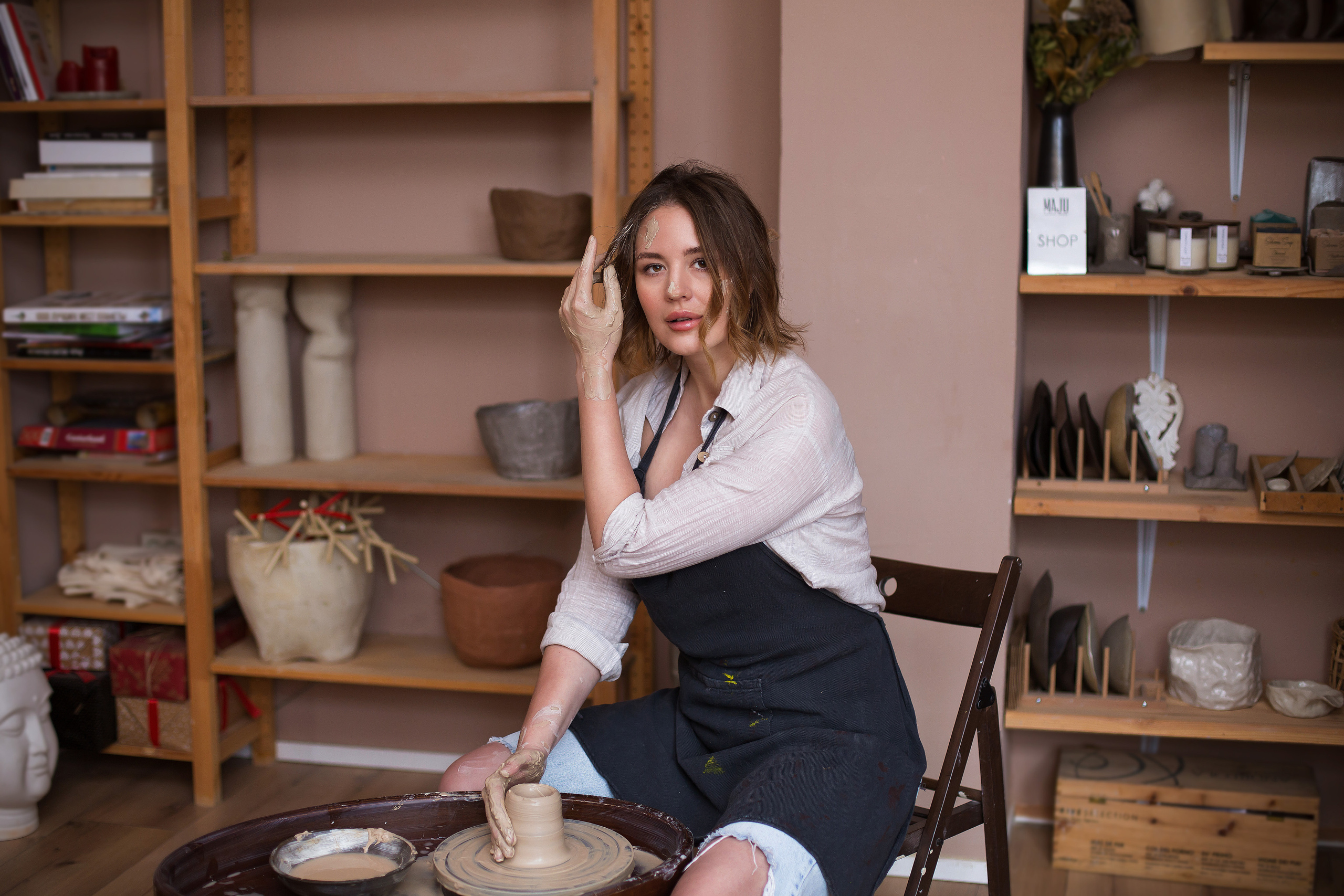 портрет девушки в фартуке за гончарным кругом