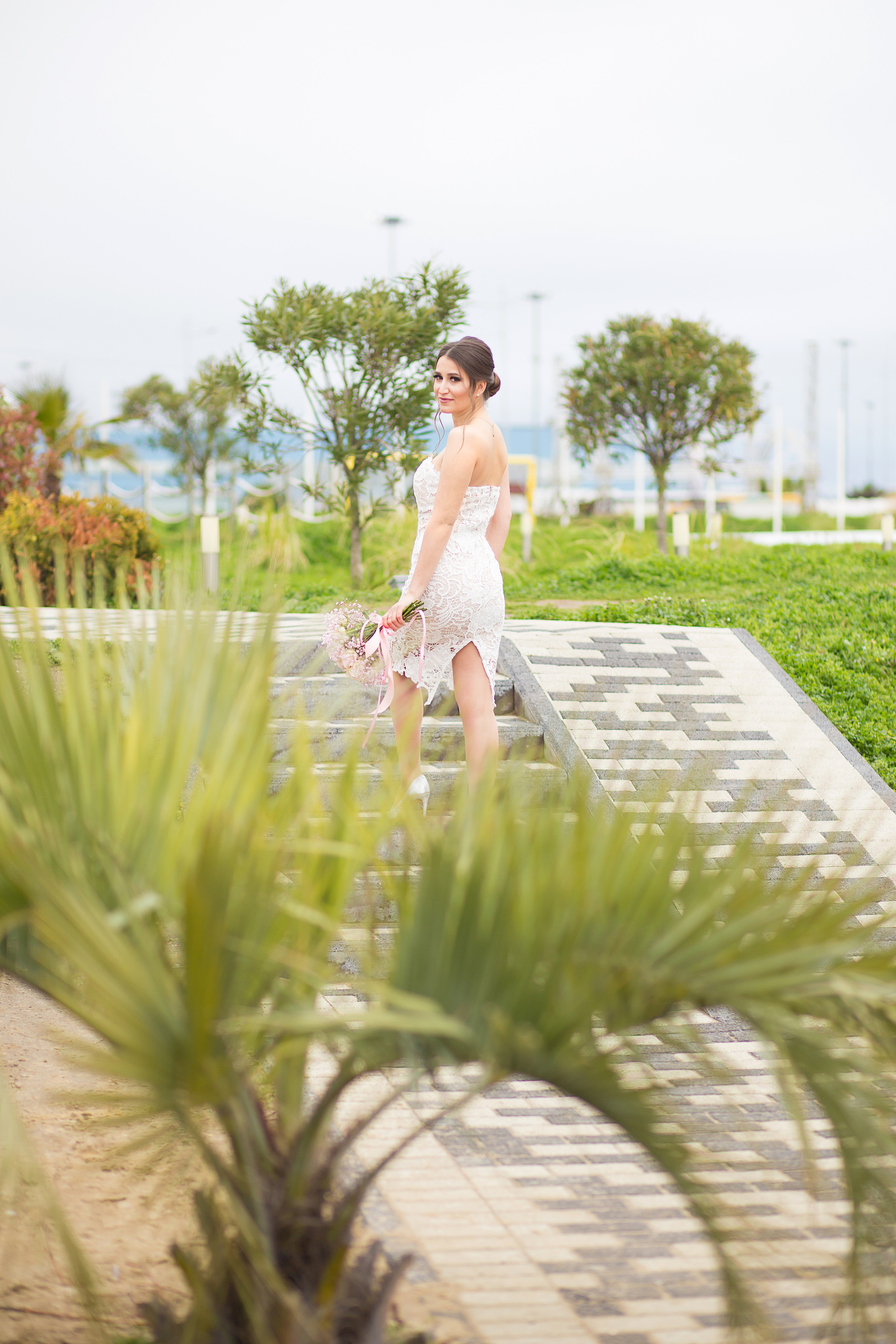 невеста в белом платье стоит возле пальм