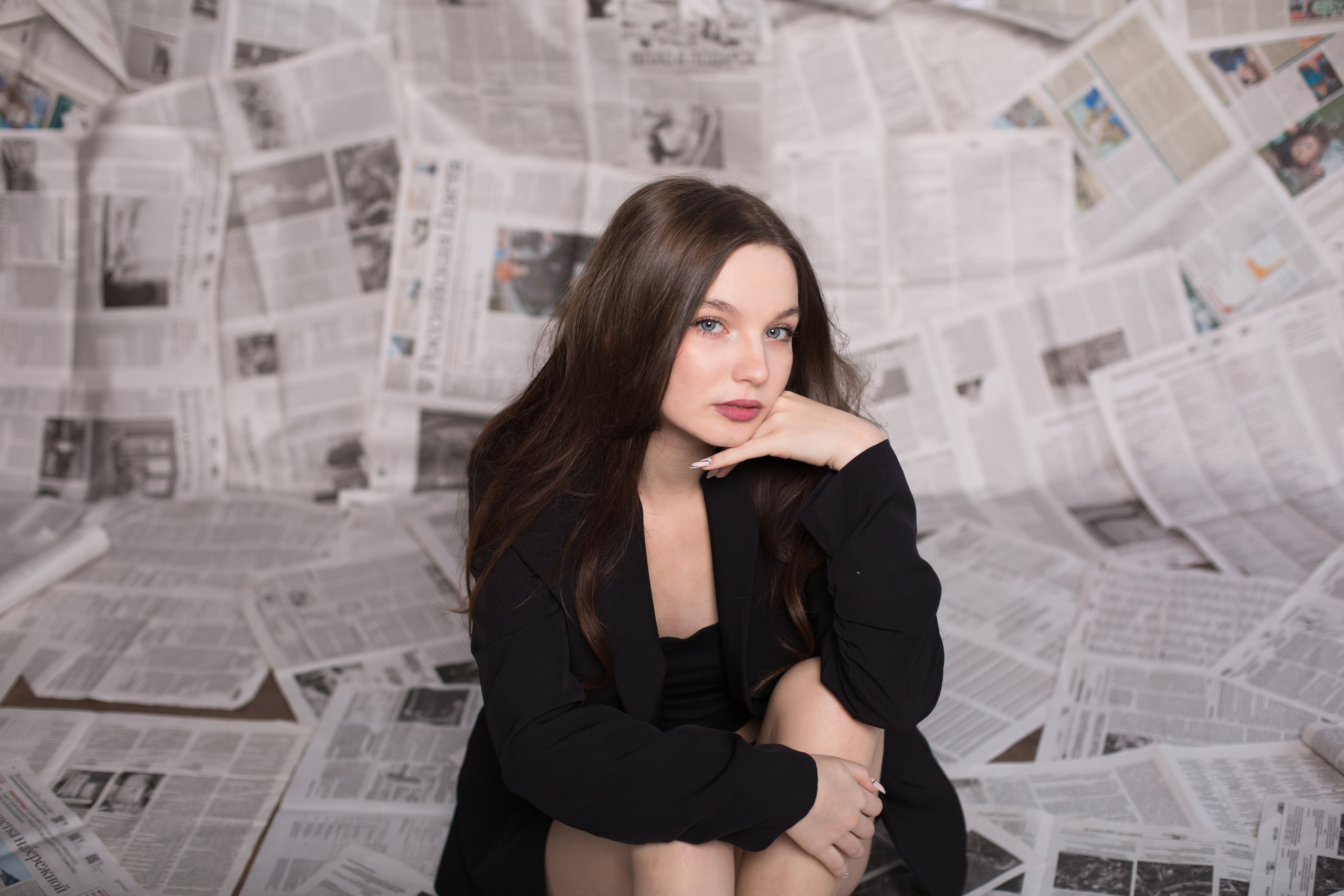 портрет девушки в пиджаке на фоне газет