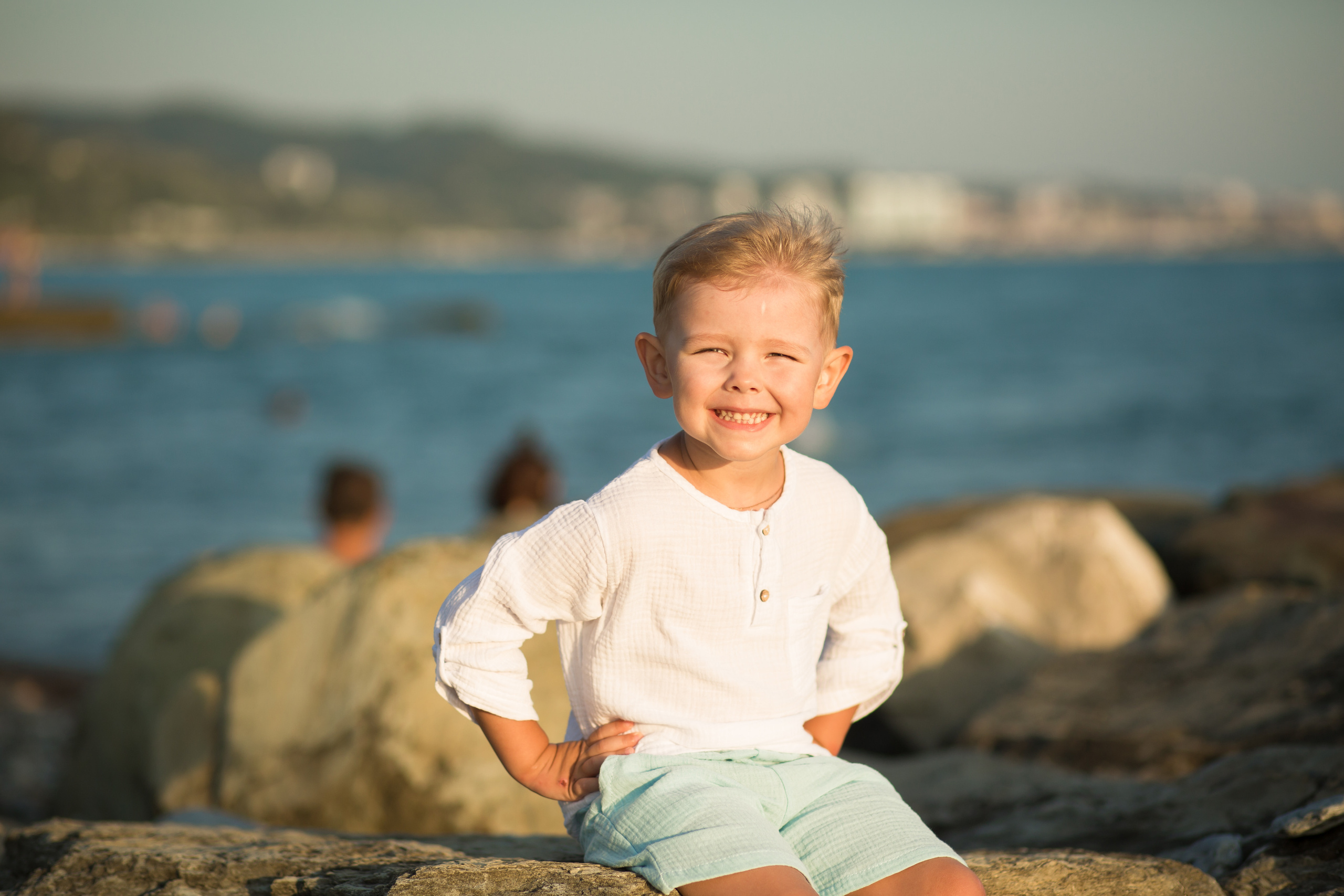 мальчик сидит веселый у моря