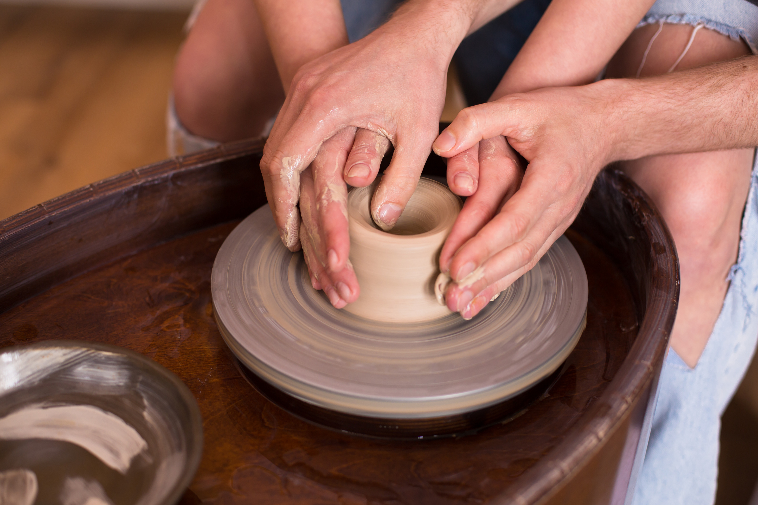 руки девушки и парня за гончарным кругом