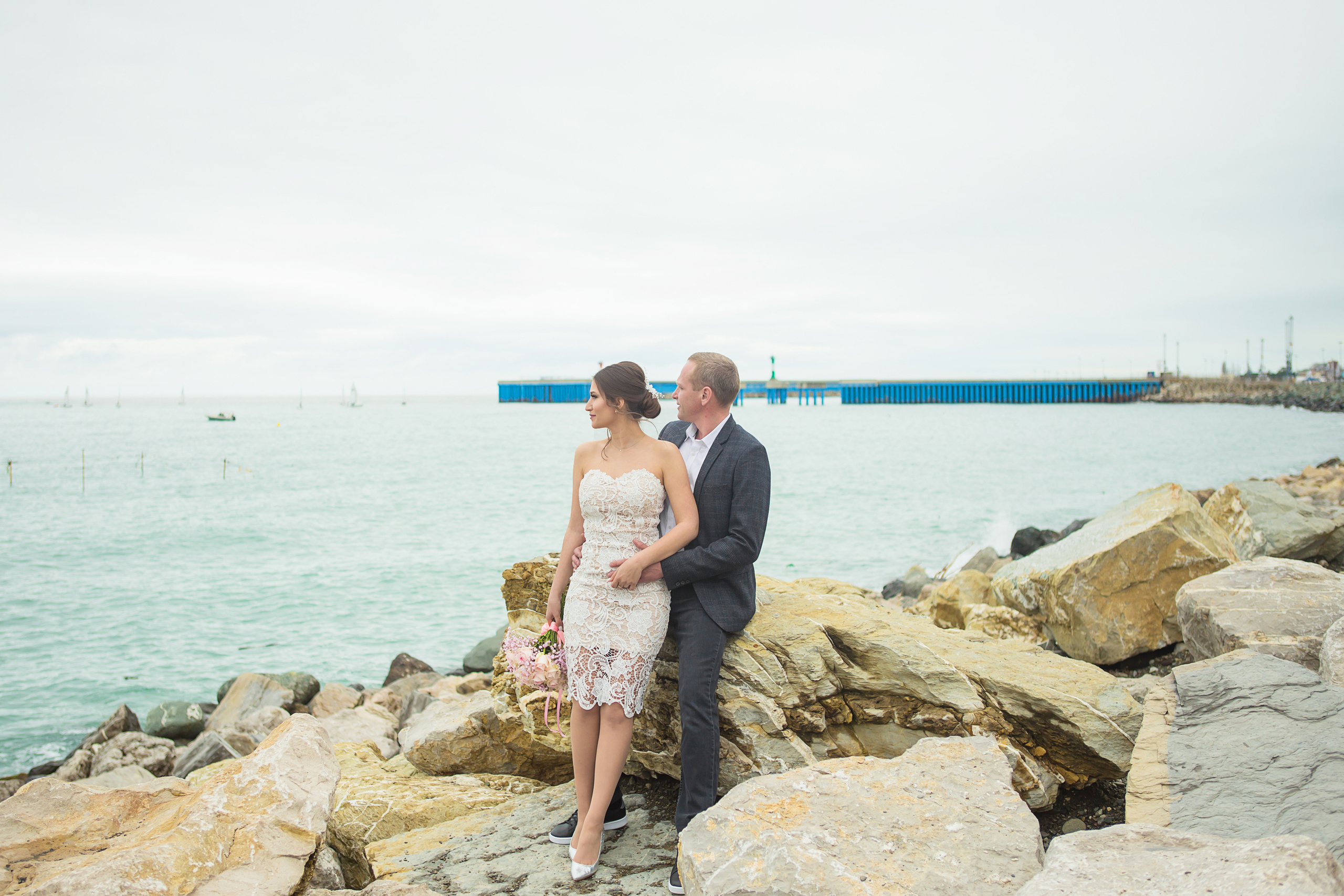 невеста и жених стоят на фоне моря